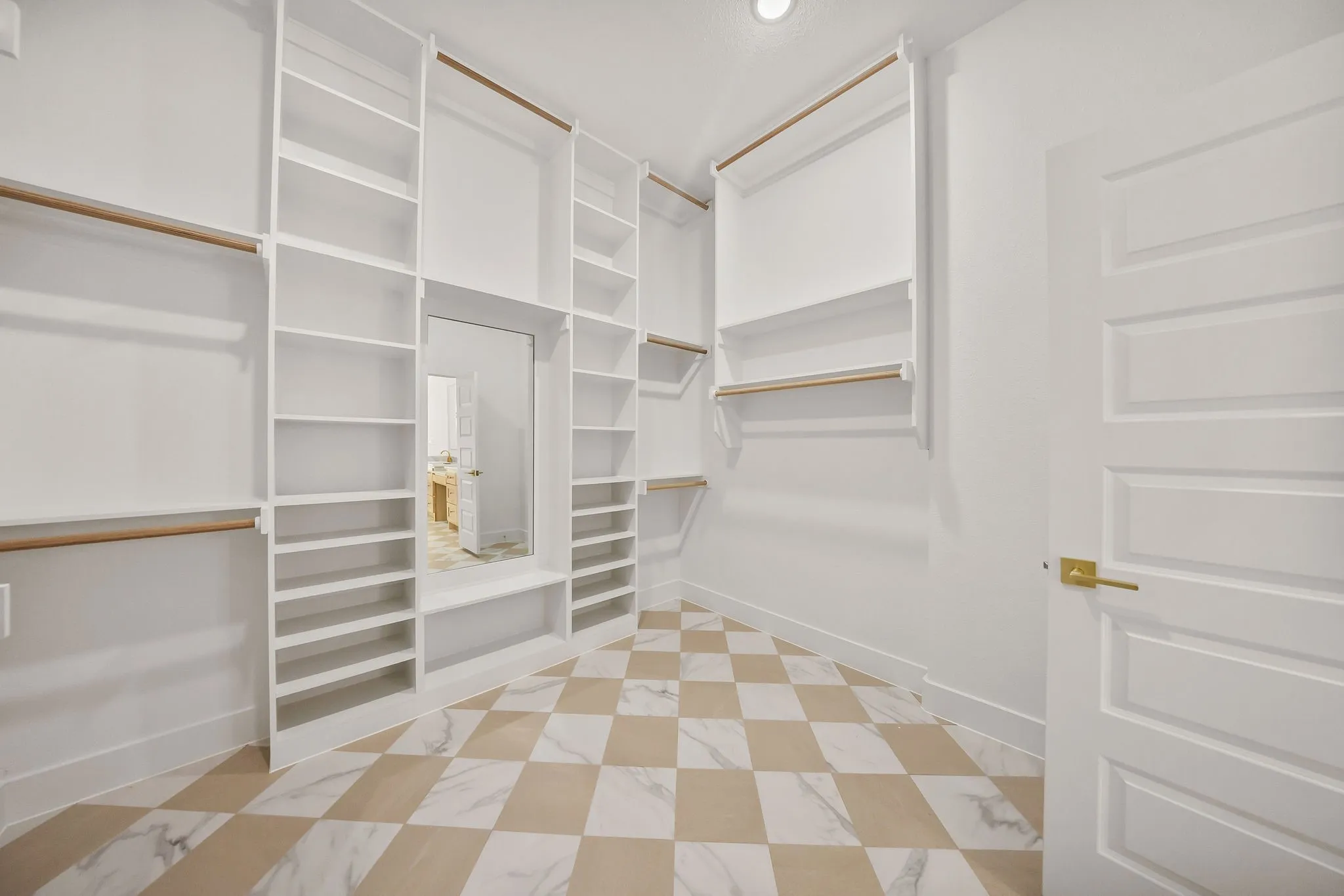 Built-in white shelving and hanging rods with a full-length mirror