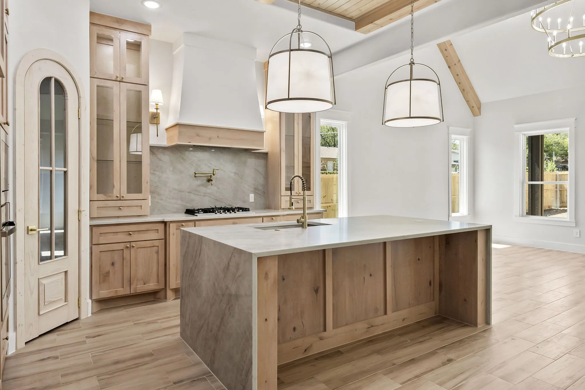 Kitchen featuring a large central island with a light-toned countertop, a range with a built-in exhaust hood, and light wood-finish cabinetry