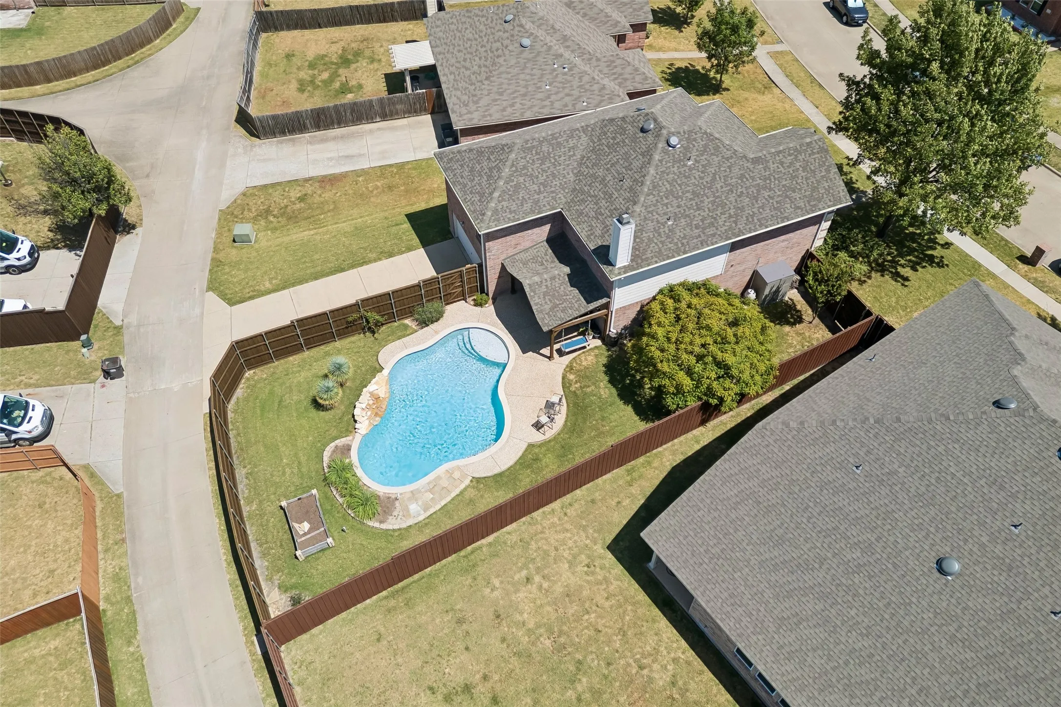 A Backyard Designed Around the Pool – From above, the generous lot reveals a well-planned outdoor layout with the swimming pool at the center, a covered cedar patio, surrounding deck space, and plenty of lawn remaining around it.