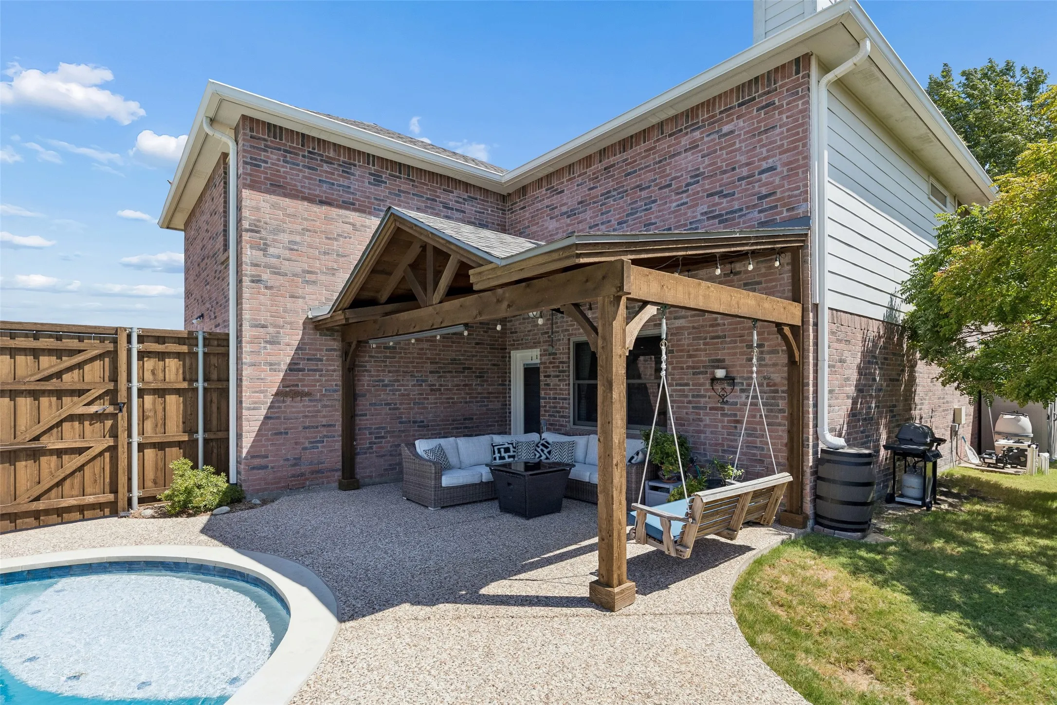 Covered Cedar Patio Steps from the Pool – Heavy timber construction gives the covered patio architectural presence while creating shade beside the pool and a natural transition from indoor living to the backyard.