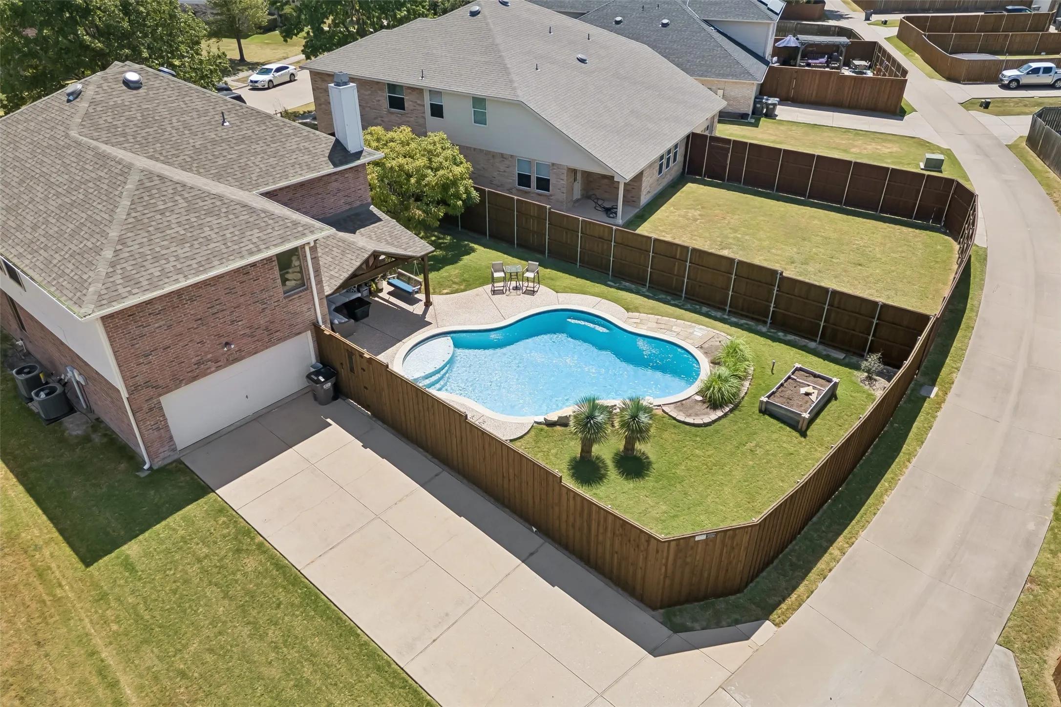 Room for Parking and Outdoor Living – This aerial view shows the long driveway, oversized two-car garage, fenced backyard, pool, covered patio, and usable green space that give the property both everyday function and recreational appeal.