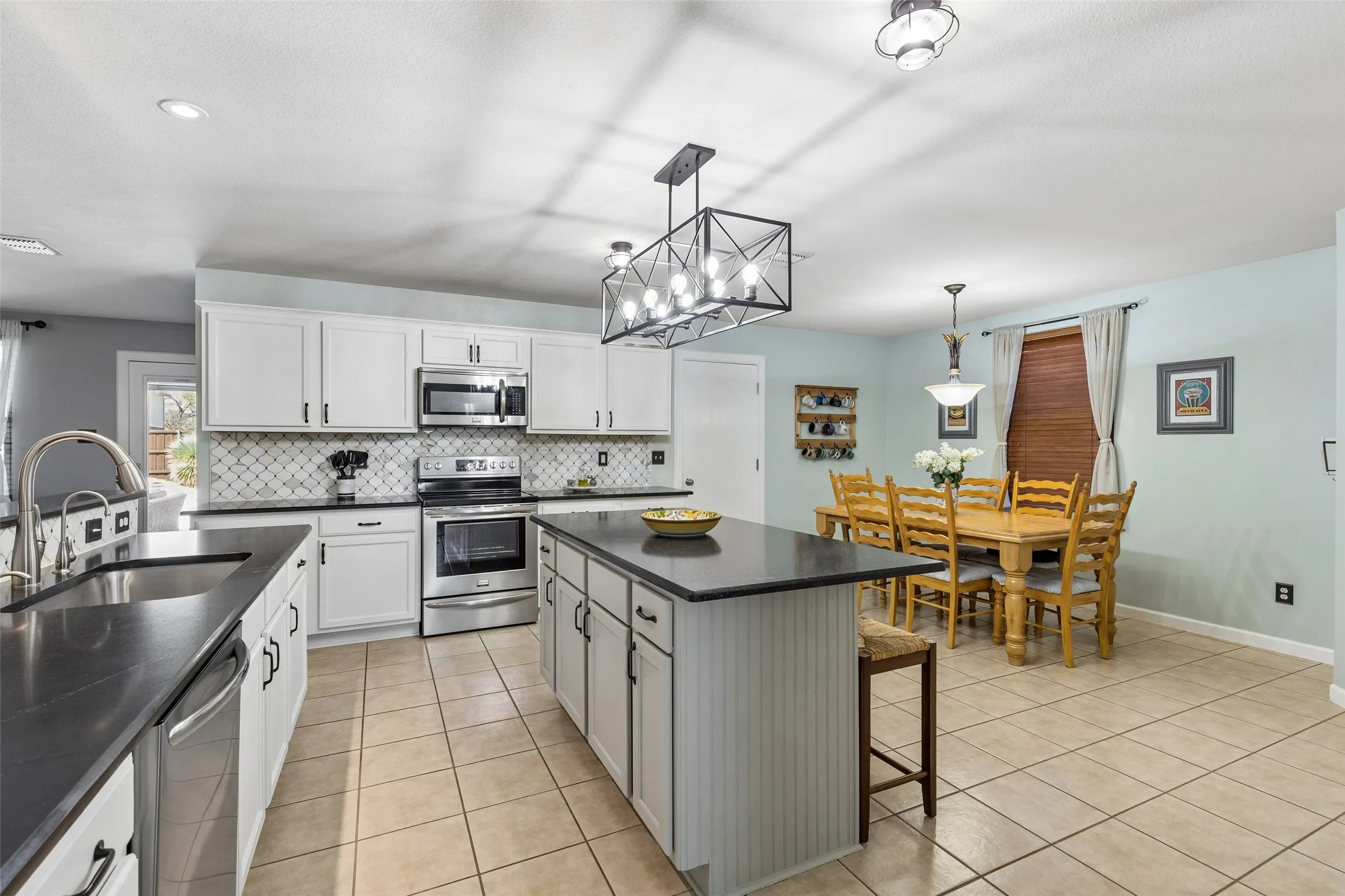 Updated Finishes, Abundant Storage – White cabinetry, updated hardware, designer tile backsplash, smooth-top range, built-in microwave, and stainless appliances give the kitchen a fresh look without sacrificing storage or function.