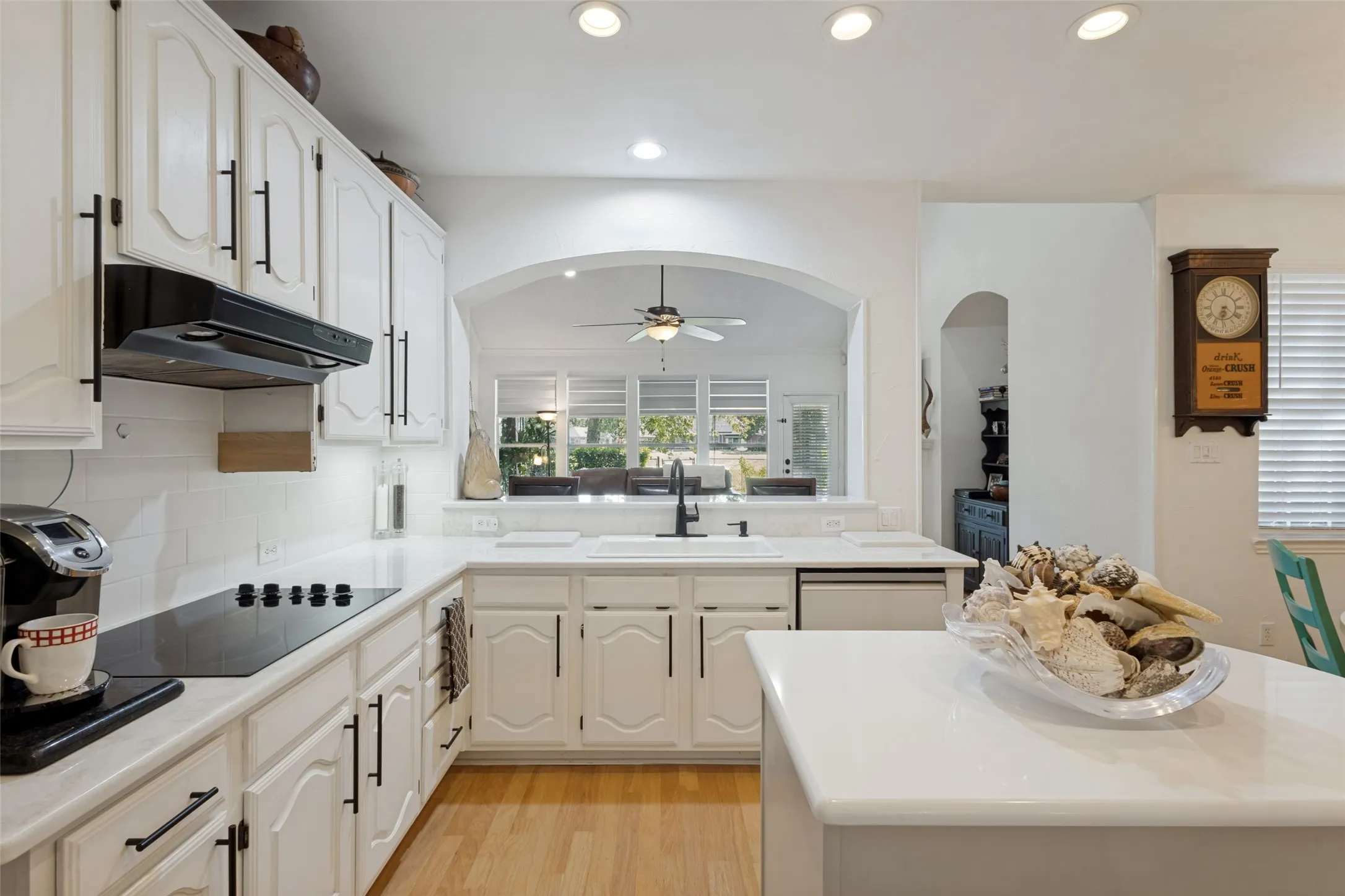 Installed designer quartz counter tops and white subway tile backsplashes. Soft white cabinetry with some glass displays and black iron hardware. Open to  the family room and casual dining.