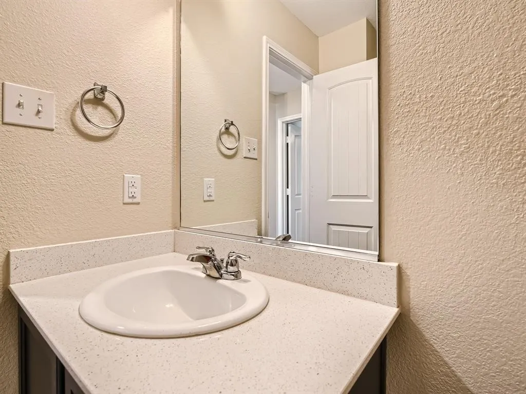 Bathroom vanity featuring a white oval sink, chrome faucet, and light-colored solid surface countertop