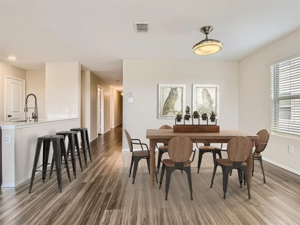 Wood-finish flooring throughout, dining area with a flush mount light fixture, and a window with horizontal blinds