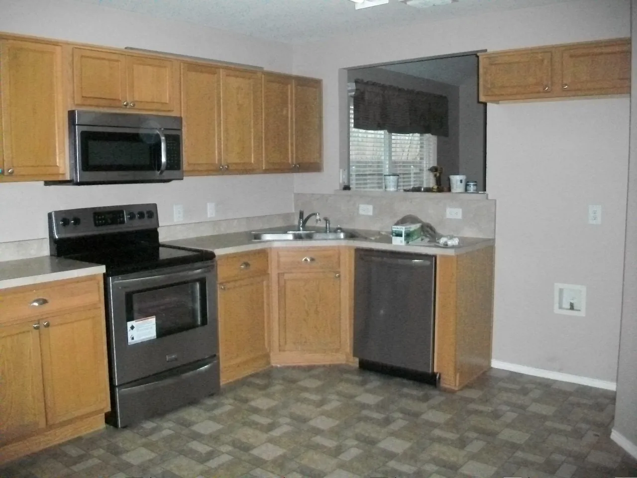 Oak cabinetry, stainless steel microwave, stainless steel range, stainless steel dishwasher, and patterned flooring