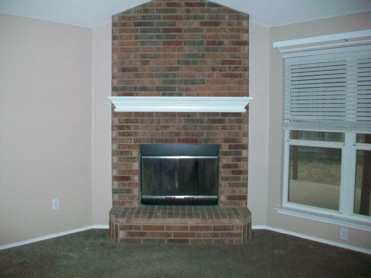 Brick fireplace with a white mantel, glass fire screen, and hearth