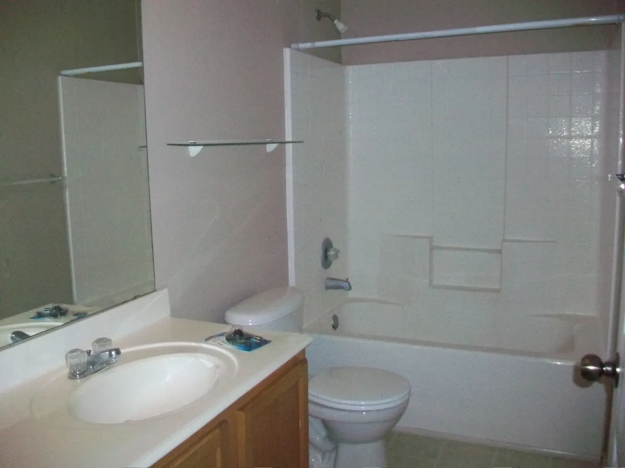 Built-in bathtub with shower, toilet, single vanity with integrated sink, wood-finish cabinetry, and wall-mounted mirror