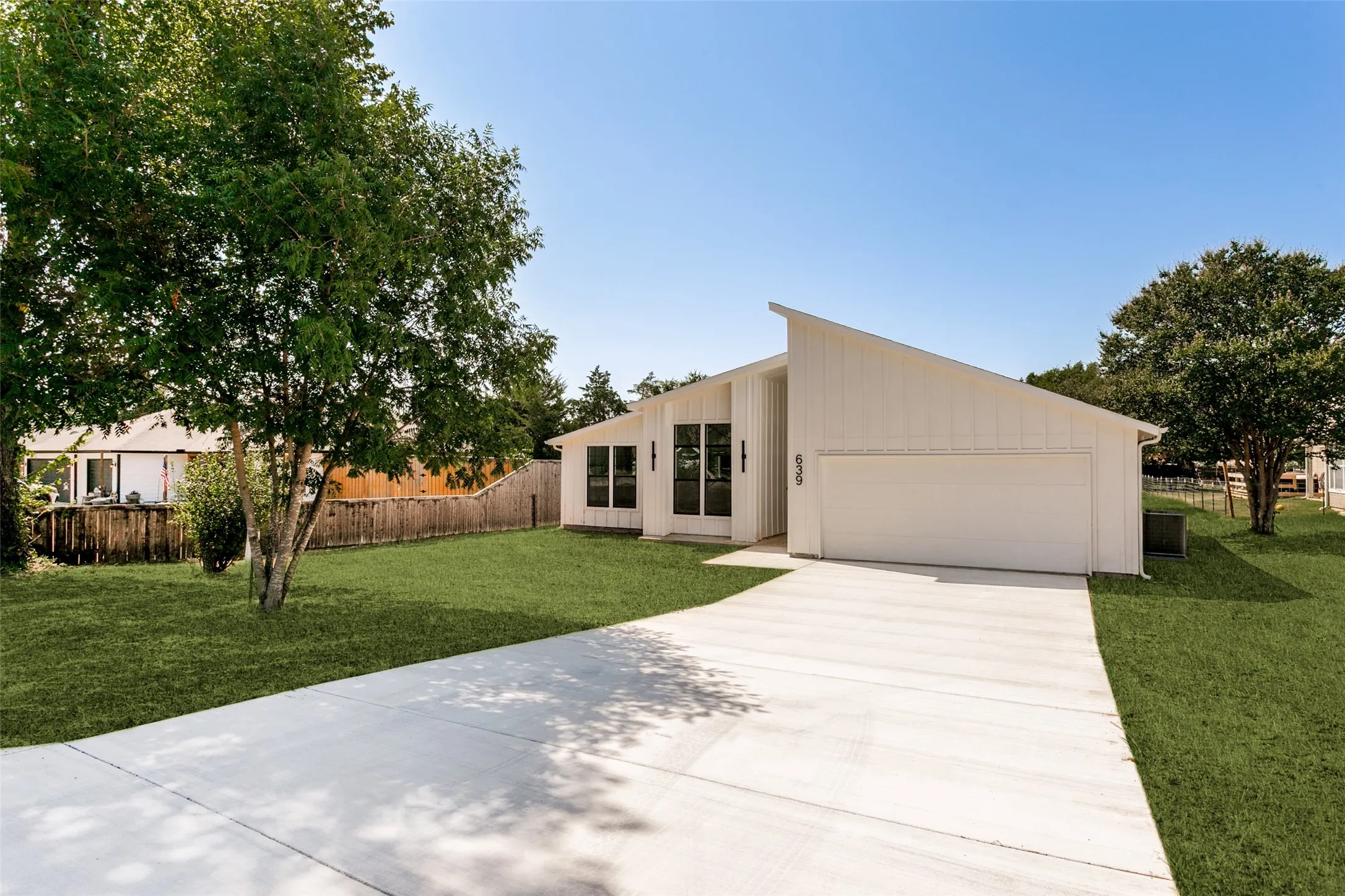 Modern architectural exterior with a pitched roofline, vertical white siding, and a large attached garage