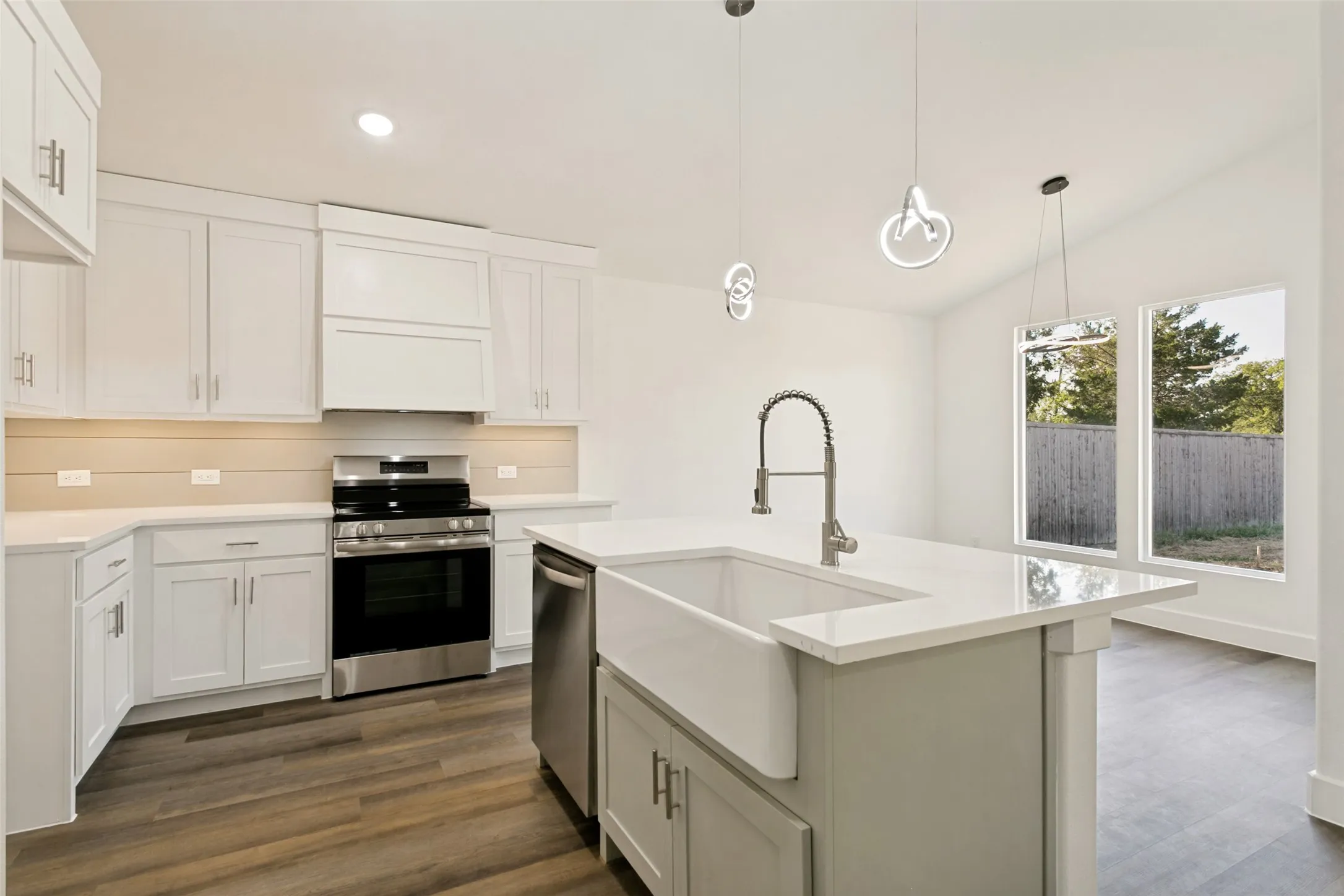Modern kitchen featuring white shaker cabinetry, stainless steel appliances, a center island with a farmhouse sink, and wood-finish flooring