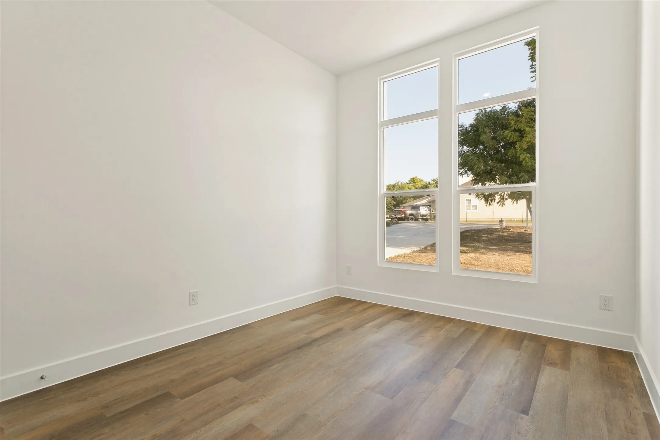 Tall windows with white frames, wood-finish flooring, and white painted walls