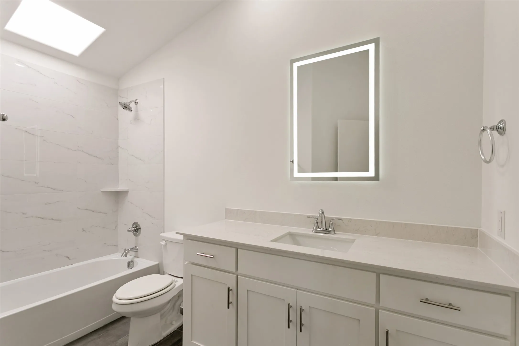 White vanity with an integrated sink, gray quartz-finish countertop, and brushed nickel hardware