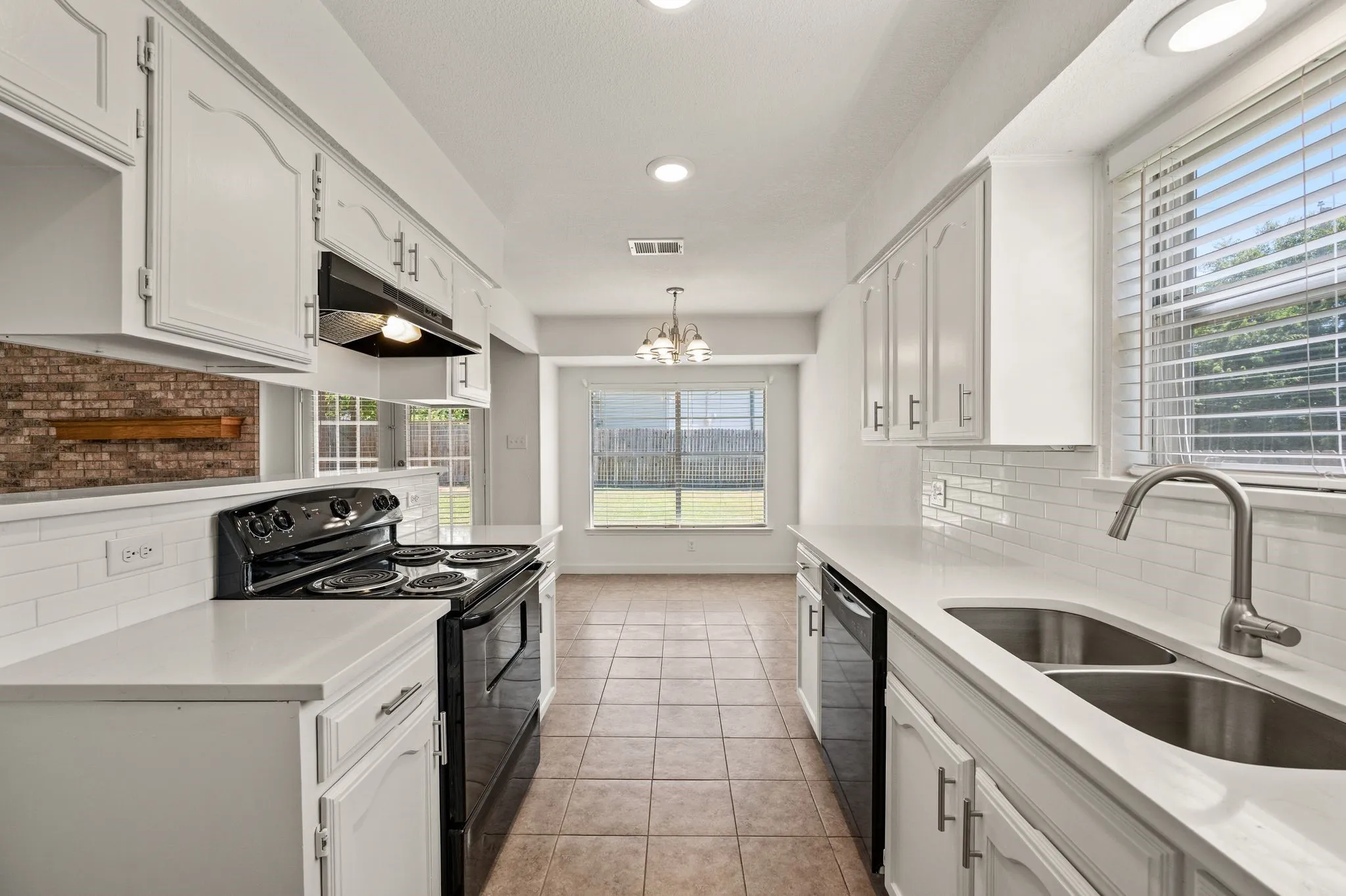 Kitchen featuring white cabinetry, solid surface countertops, white subway tile backsplash, and tile flooring