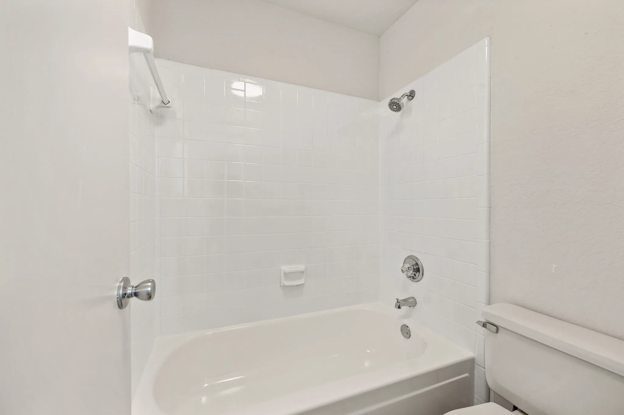 Clean bathroom featuring a built-in bathtub with subway tile surround, chrome fixtures, and a semi-frameless glass enclosure