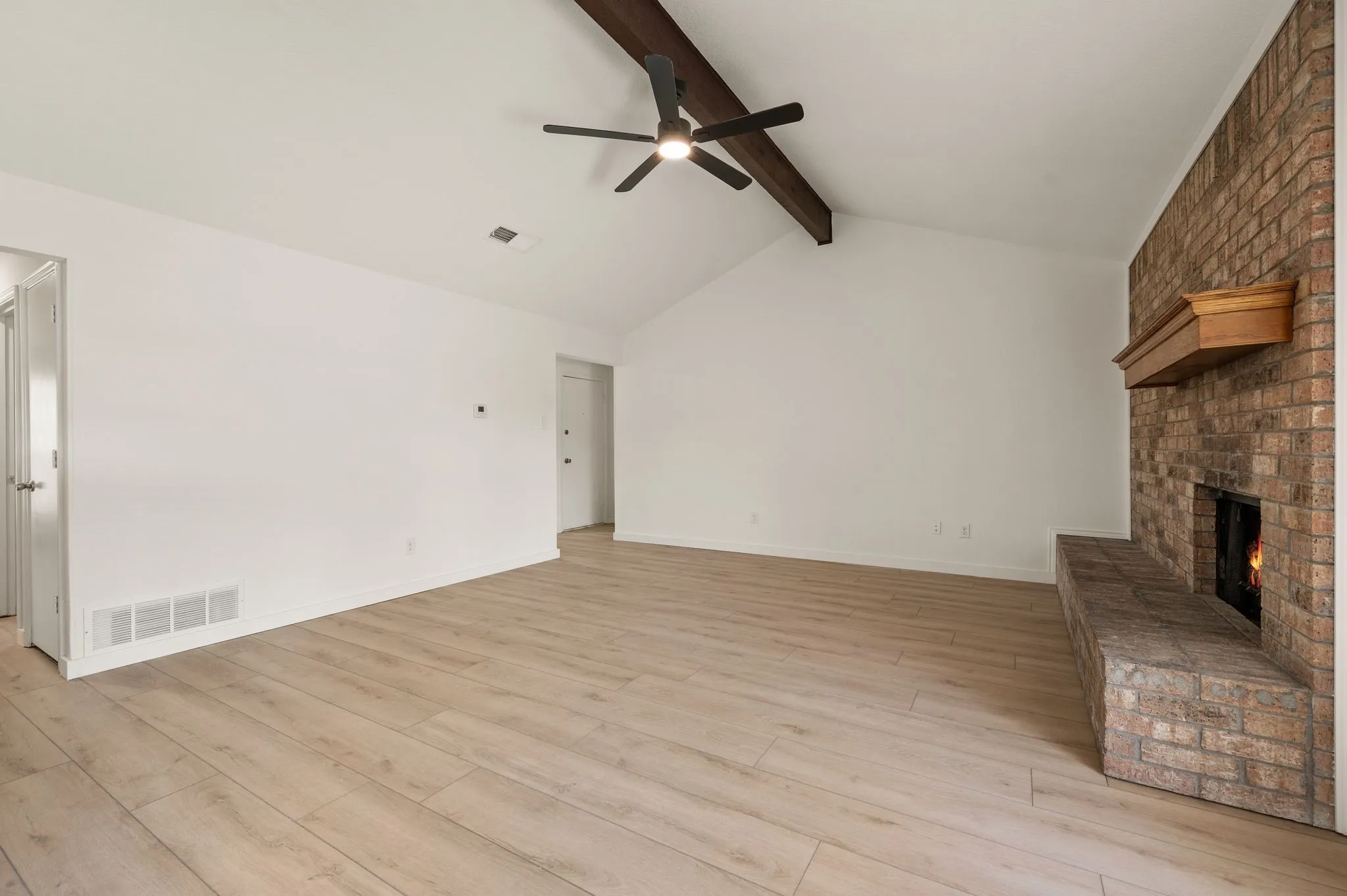 Spacious open living area with soaring vaulted ceilings, wood-finish flooring throughout, and a ceiling fan