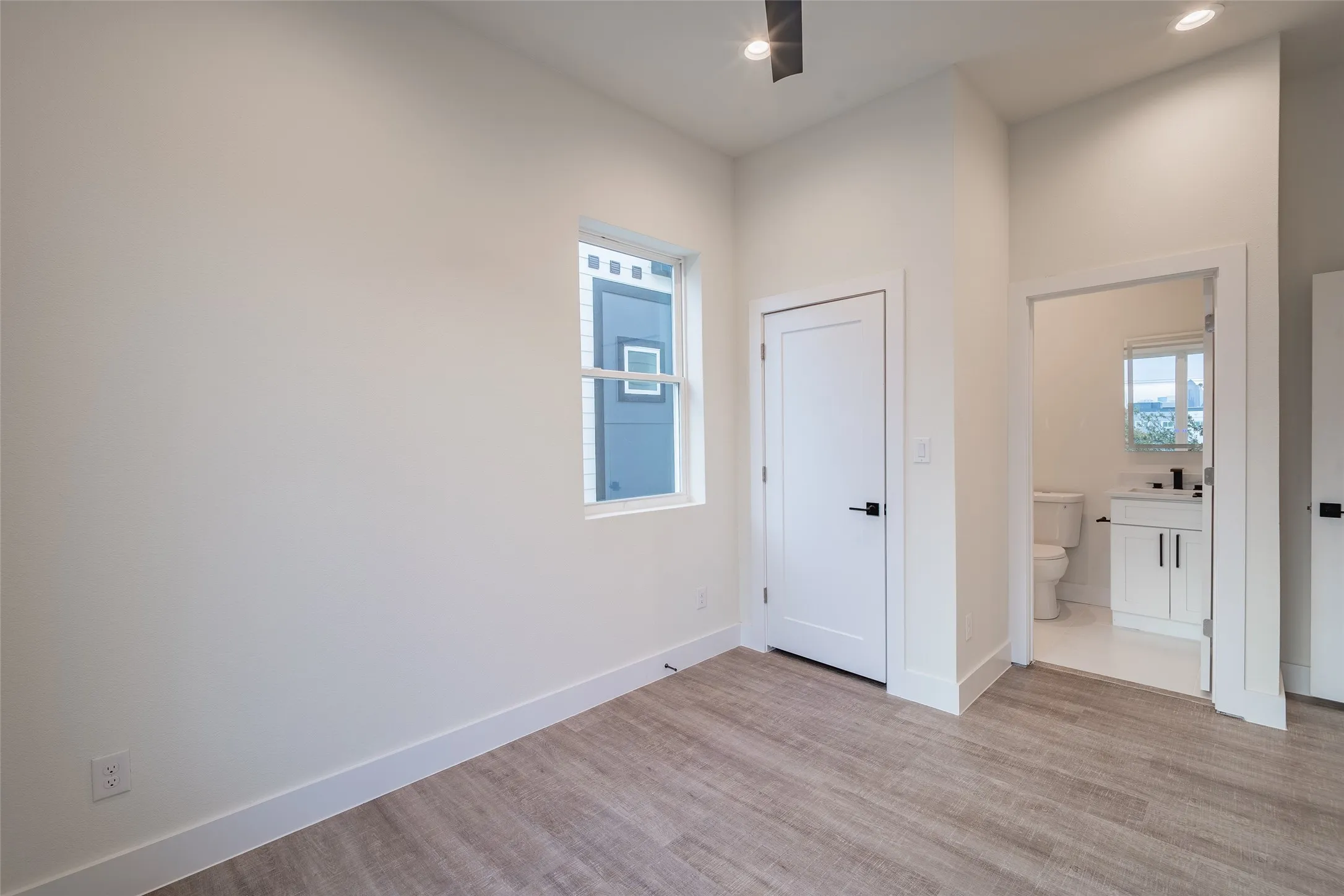 Bedroom with light hardwood / wood-style flooring and ensuite bath