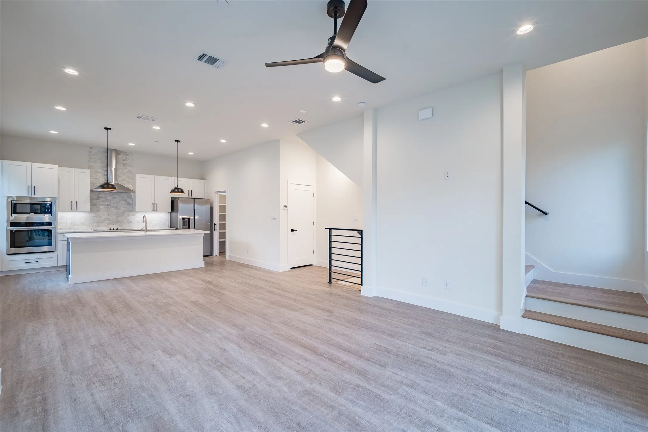 Unfurnished living room featuring light wood-type flooring, ceiling fan, and sink