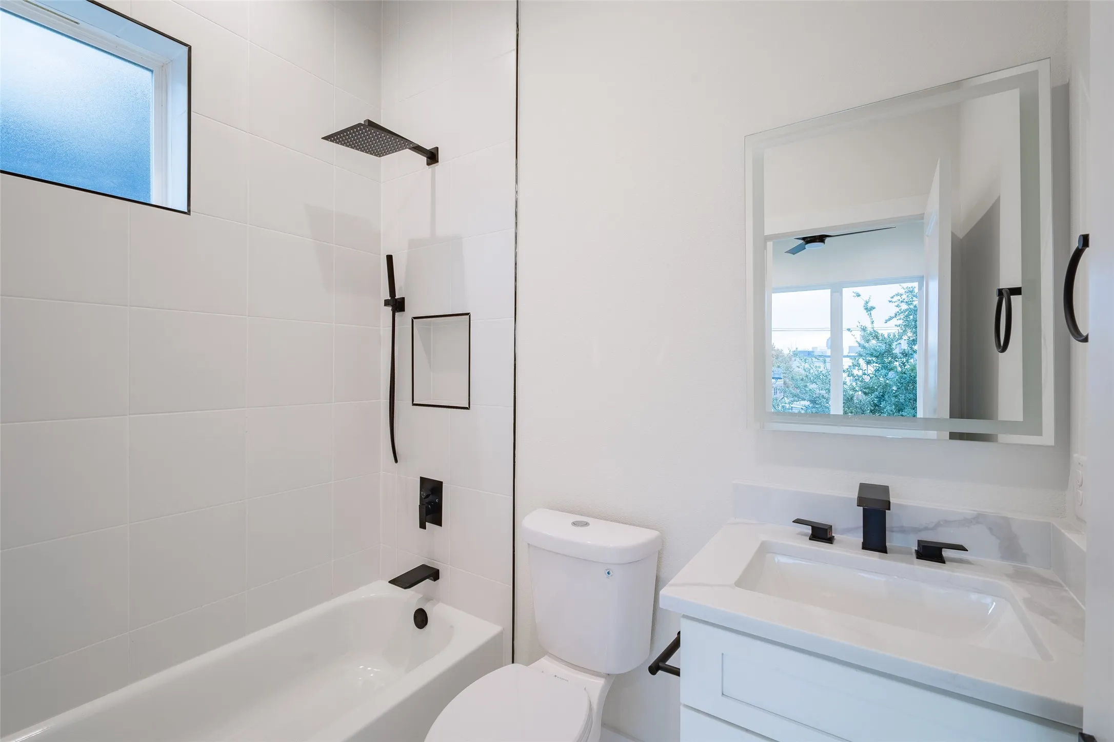 Full bathroom with toilet, vanity, tiled shower / bath combo, and ceiling fan