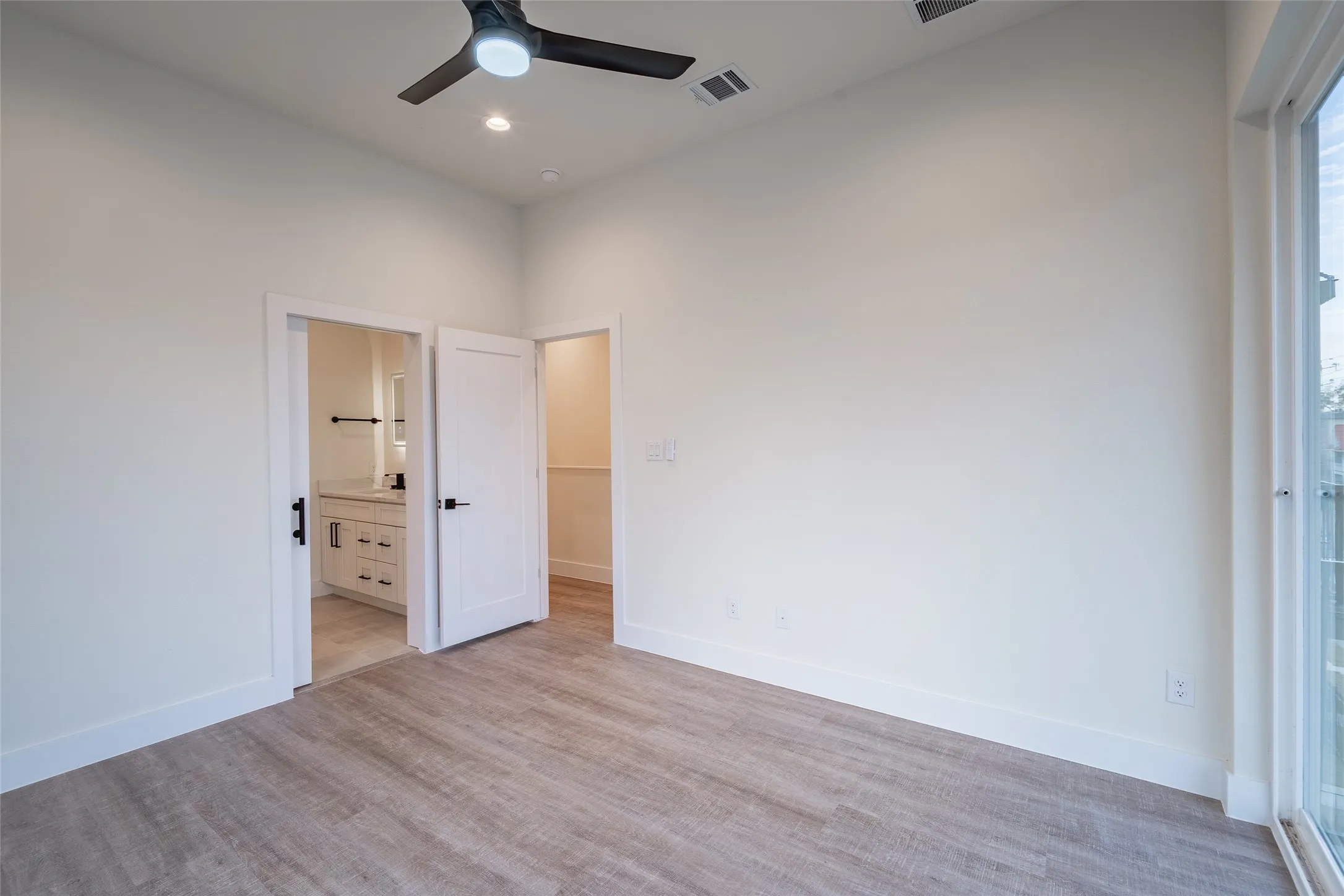 Bedroom featuring light hardwood / wood-style floors, ensuite bath, and ceiling fan