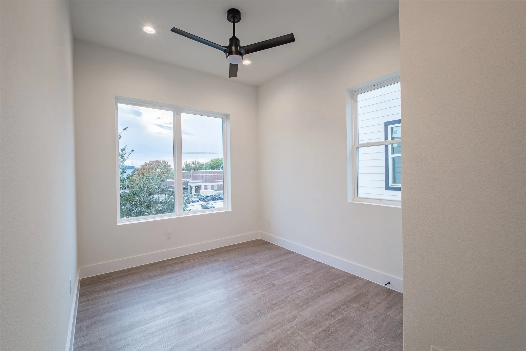 Unfurnished room featuring plenty of natural light, ceiling fan, and light wood-type flooring