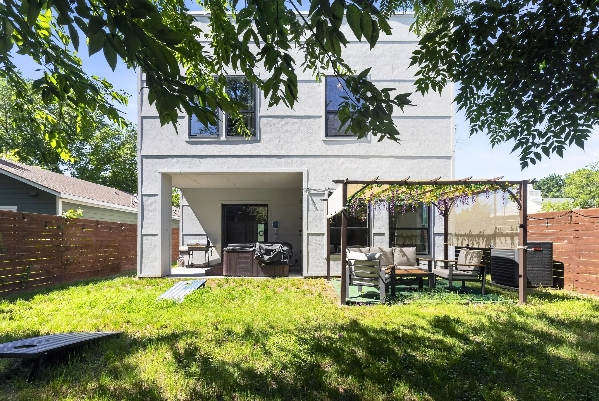 Expansive backyard featuring a manicured lawn, a covered patio, and a pergola structure
