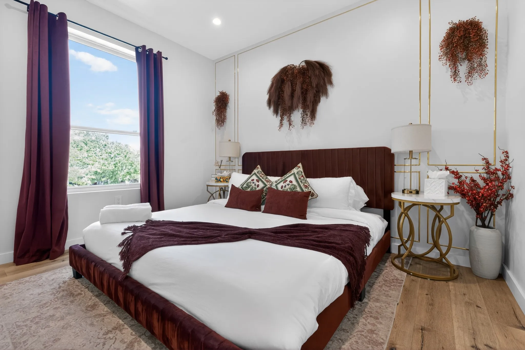 Recessed lighting, large window, rich wood-finish flooring, gold wall trim detailing, and a padded headboard