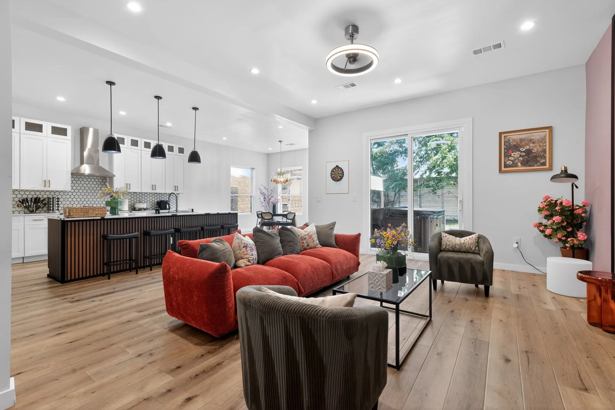 Open-concept living space featuring wood-finish flooring, recessed lighting, and a modern kitchen with pendant lights