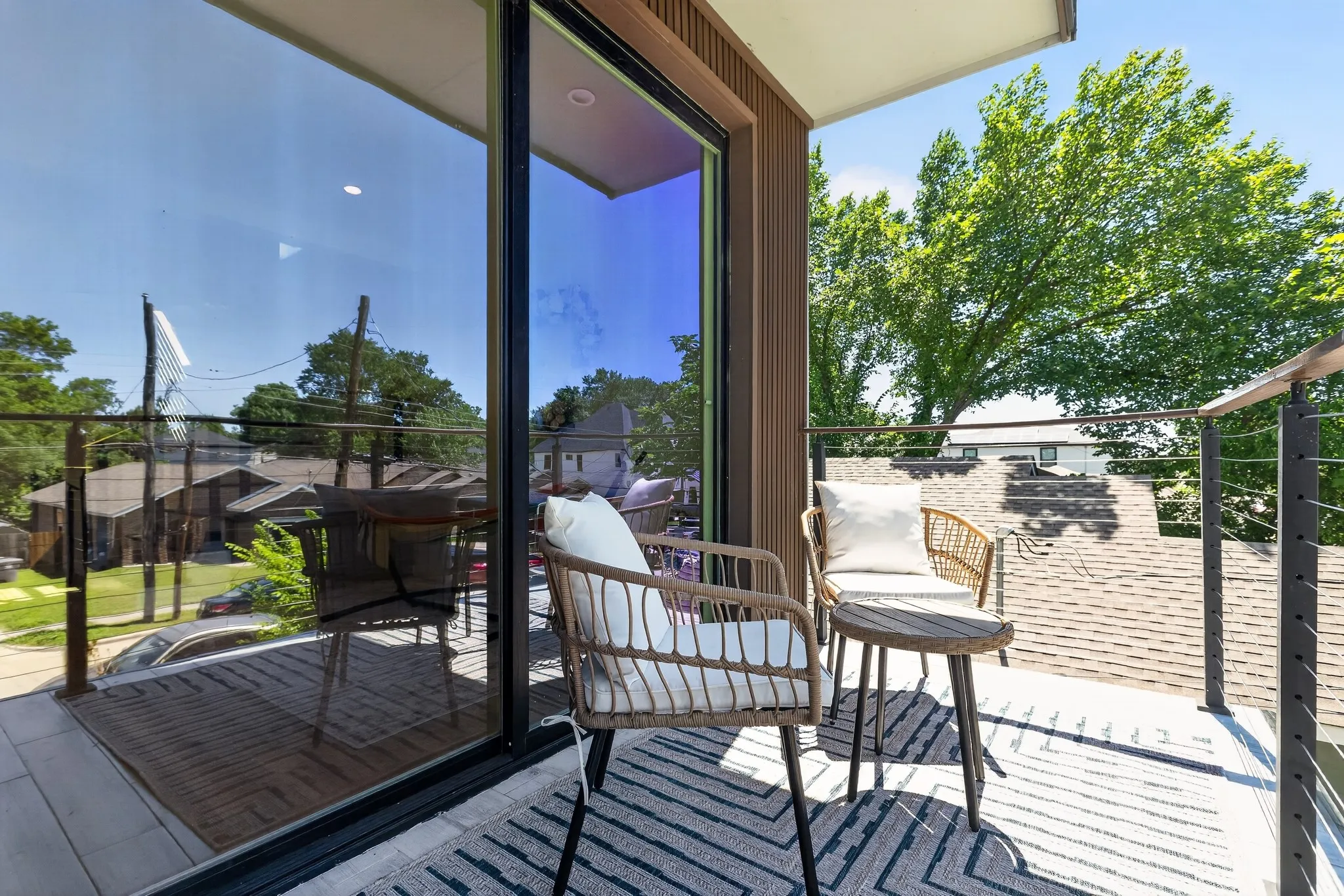 Balcony with a glass sliding door, cable railing, and wood-finish wall paneling