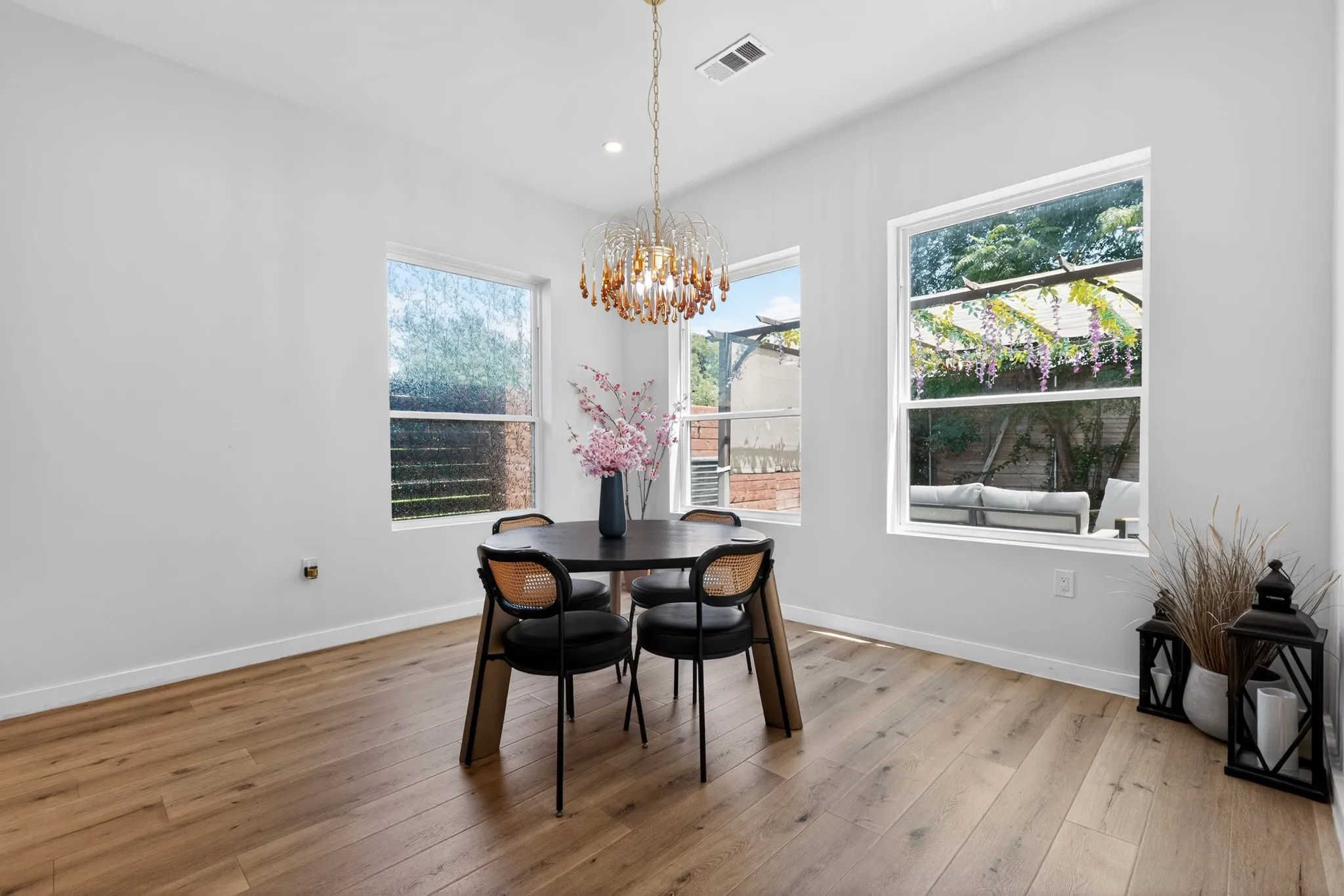 Recessed lighting and a decorative chandelier illuminate the space, complemented by multiple windows providing natural light