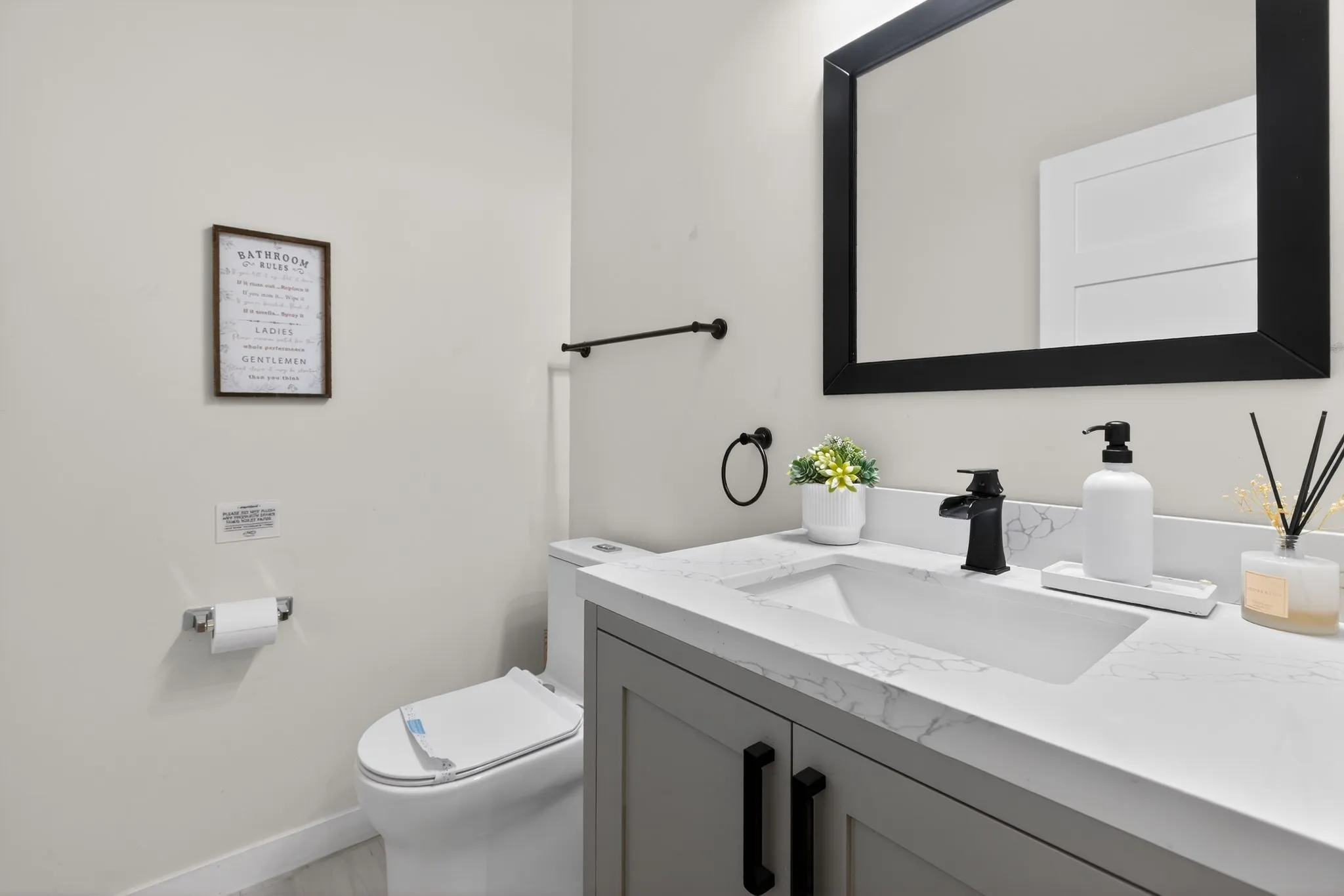 Vanity with integrated sink, black framed mirror, matte black faucet, and light gray cabinetry