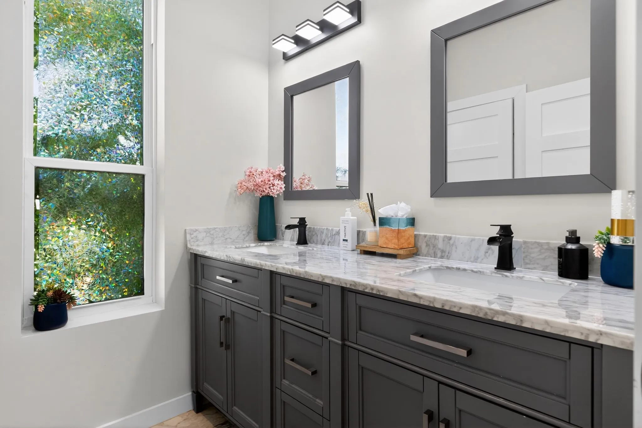 Double vanity with light-toned countertop, dual rectangular sinks, matte black faucets, and rectangular framed mirrors
