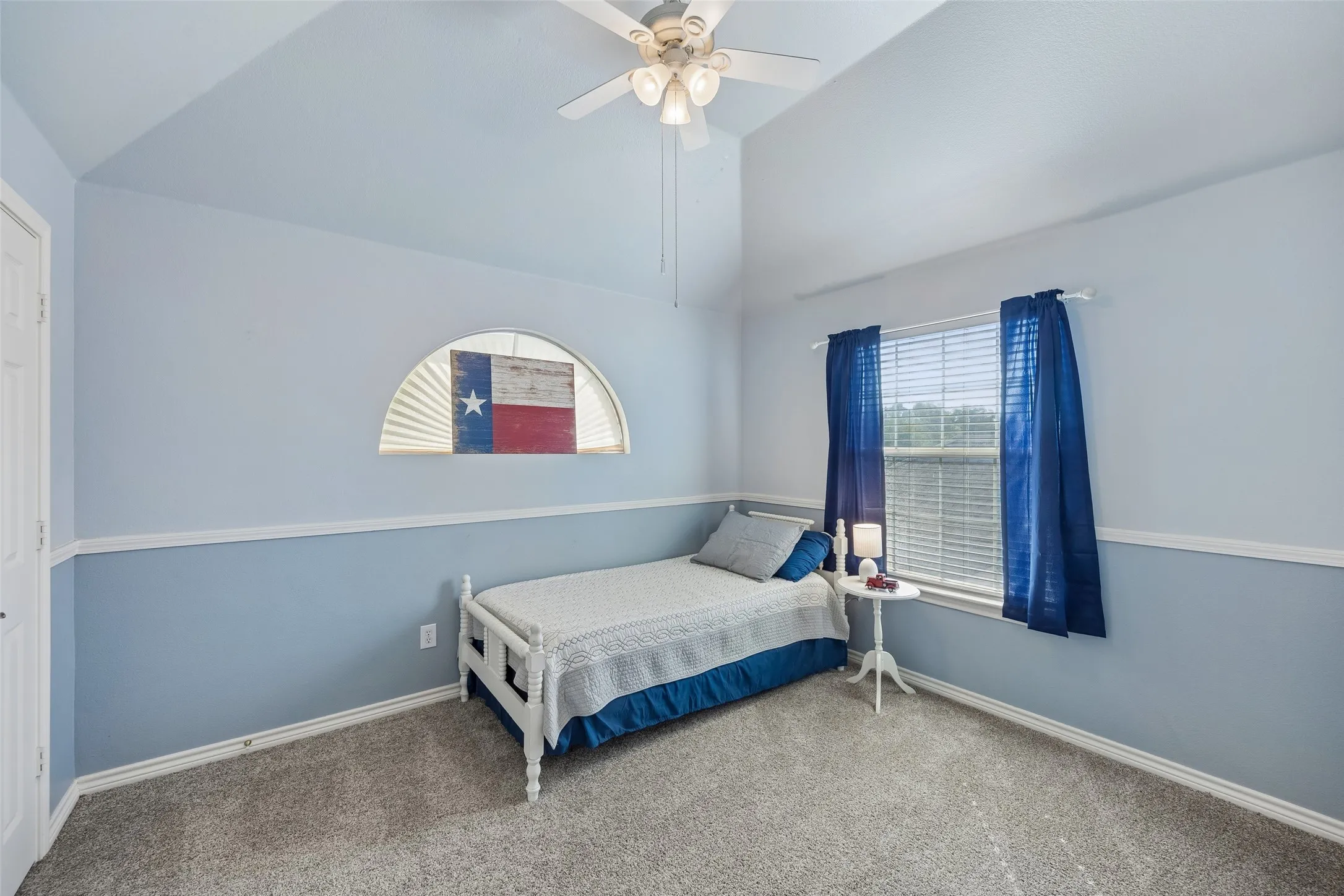 Another Generously Sized Secondary Bedroom — Vaulted ceiling lines make this bedroom feel especially open, with plenty of floor space for a larger bed and additional furniture. Chair-rail molding and a ceiling fan complete the room.