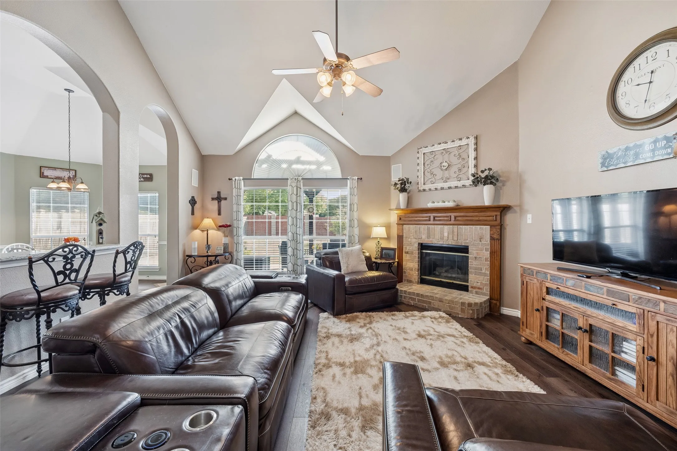 Family Room Built Around a Dramatic Focal Point — A soaring vaulted ceiling, large arched transom window, and brick fireplace with a substantial wood mantel give the family room strong architectural character, while the wide footprint provides plenty of usable living space.