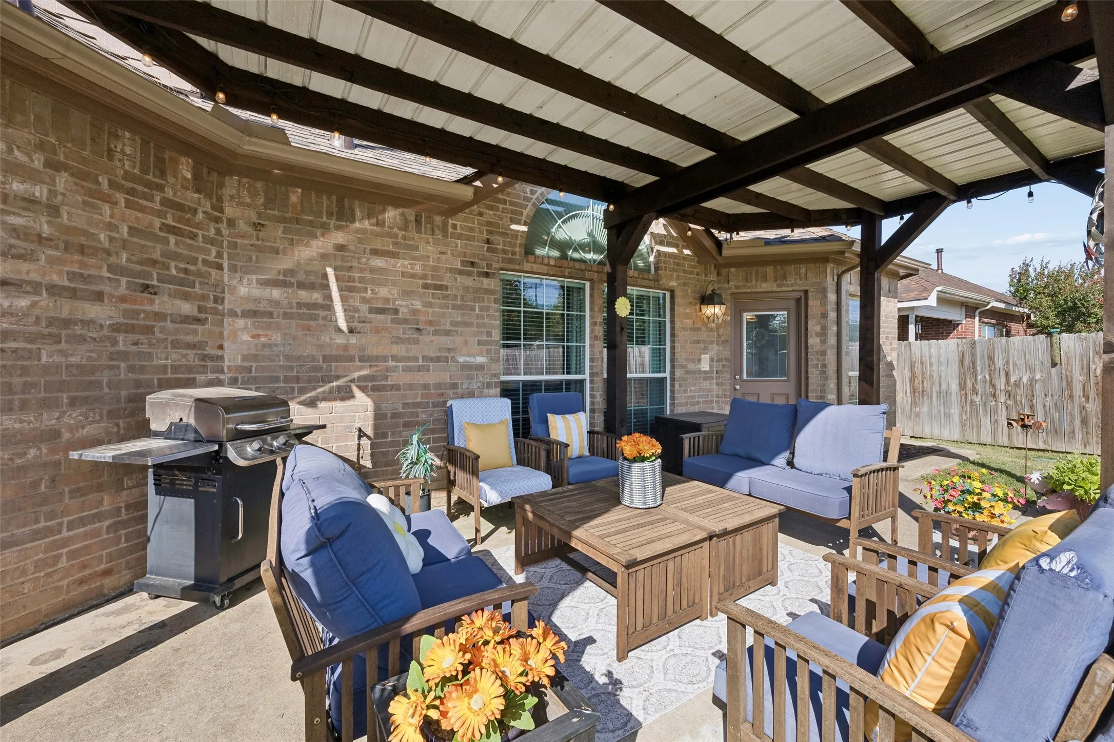 Covered Outdoor Living — The extended covered patio creates a comfortable outdoor living area with plenty of room for multiple seating arrangements. String lighting and the open view to the backyard make this a natural extension of the home's living space.