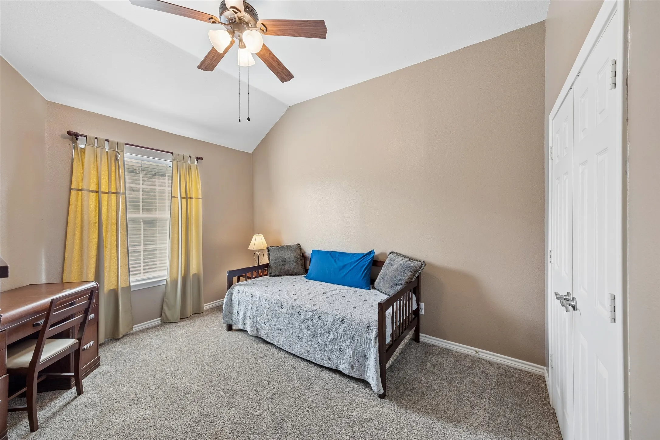 Secondary Bedroom with Vaulted Ceiling — A vaulted ceiling adds volume to this upstairs bedroom, while the arched window and additional side window bring in natural light. Chair-rail molding adds architectural detail around the room.