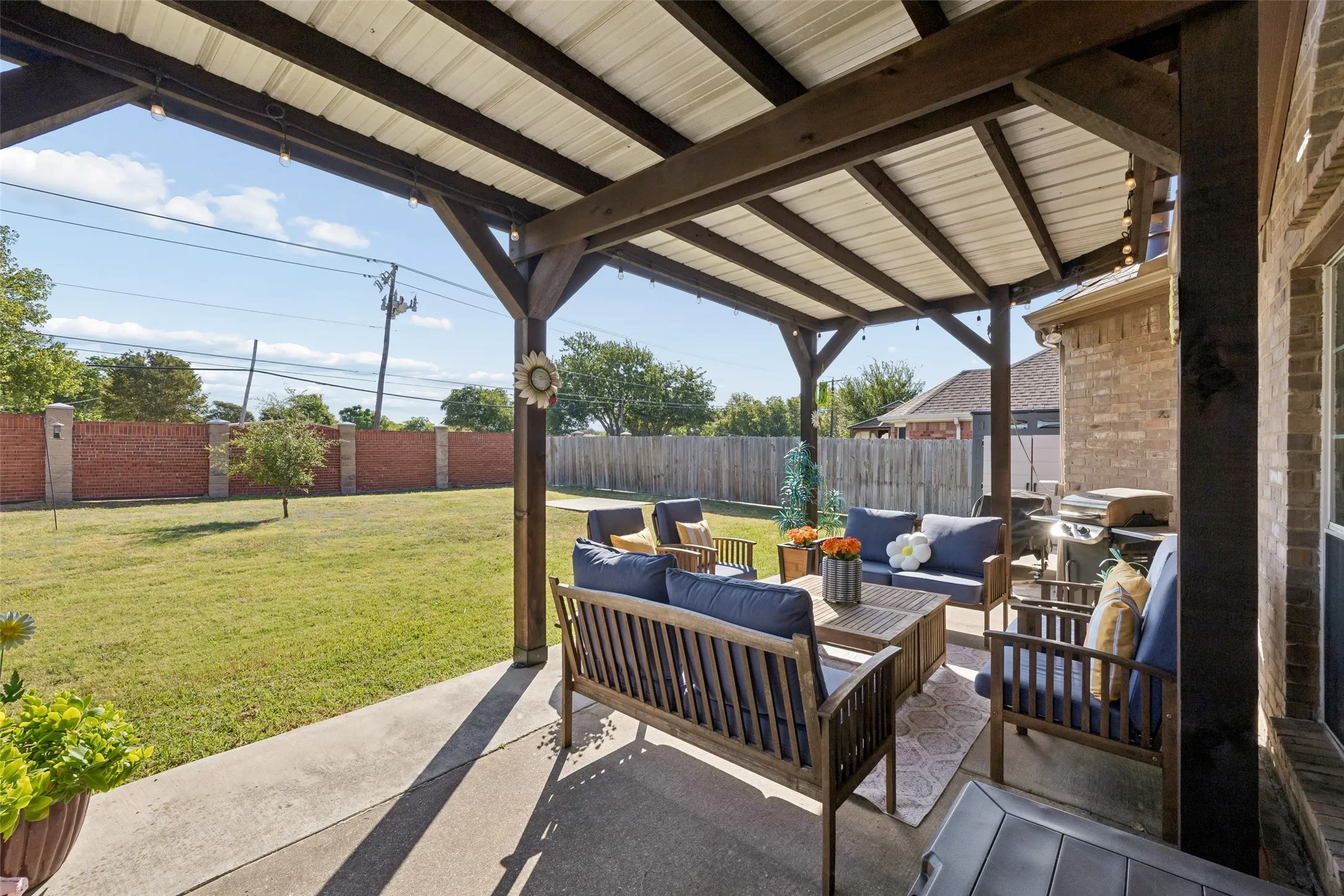 Covered Patio Plus a Large Backyard — From behind the home, the aerial view shows how the covered patio opens to a broad fenced yard, providing plenty of usable outdoor space beyond the house itself.
