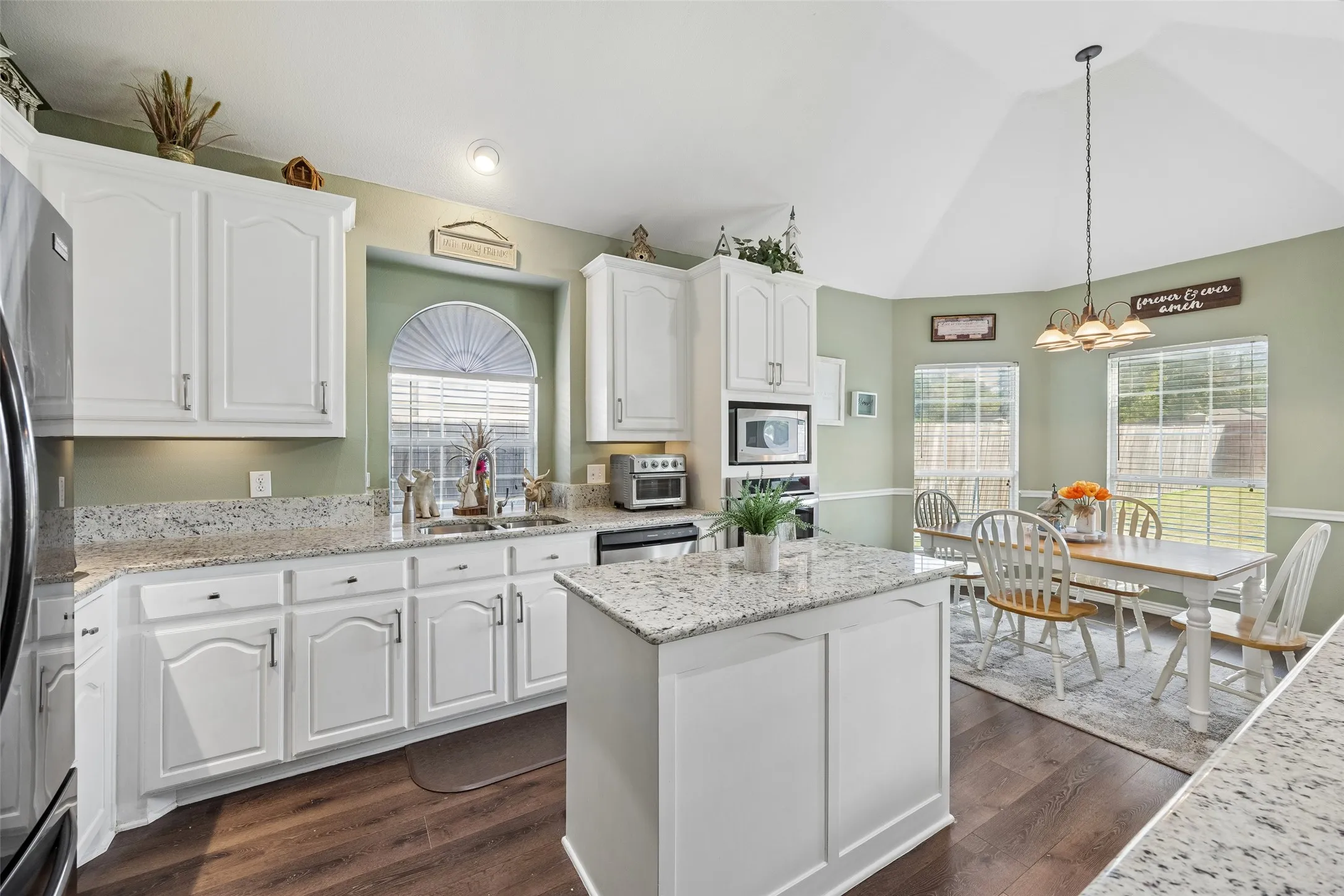 A Kitchen Designed for Storage and Workspace — Extensive cabinetry runs along multiple walls and continues beneath the breakfast bar, while a center island adds another prep surface and additional storage. Granite countertops provide generous workspace around the cooking and cleanup zones.