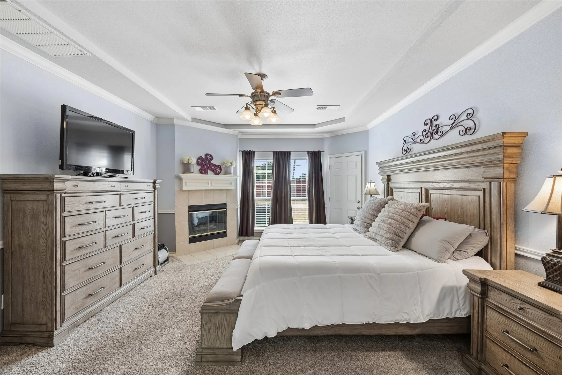 Generous Primary Suite with Backyard Views — Large enough to comfortably accommodate substantial bedroom furniture, the primary suite also features a corner fireplace and a pair of windows overlooking the backyard.