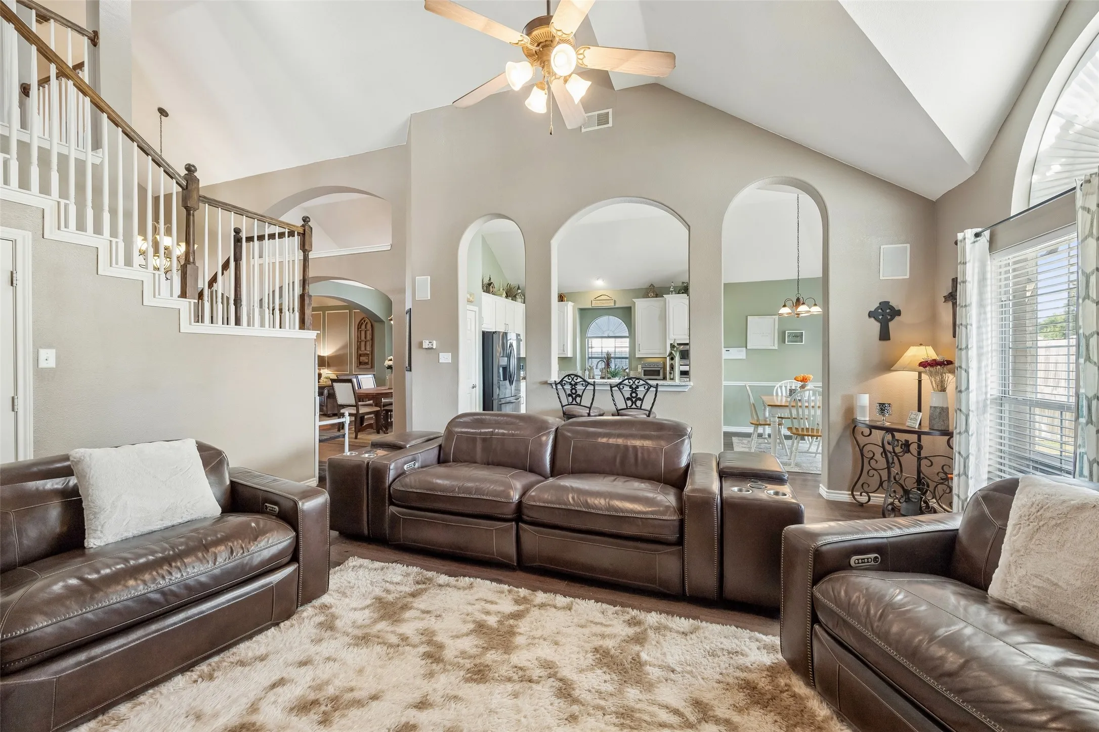 Architectural Openings Keep the Main Level Connected — From the family room, three tall arched openings frame views into the kitchen and breakfast area, while the open staircase and upstairs railing add another layer of architectural interest to the two-story layout.
