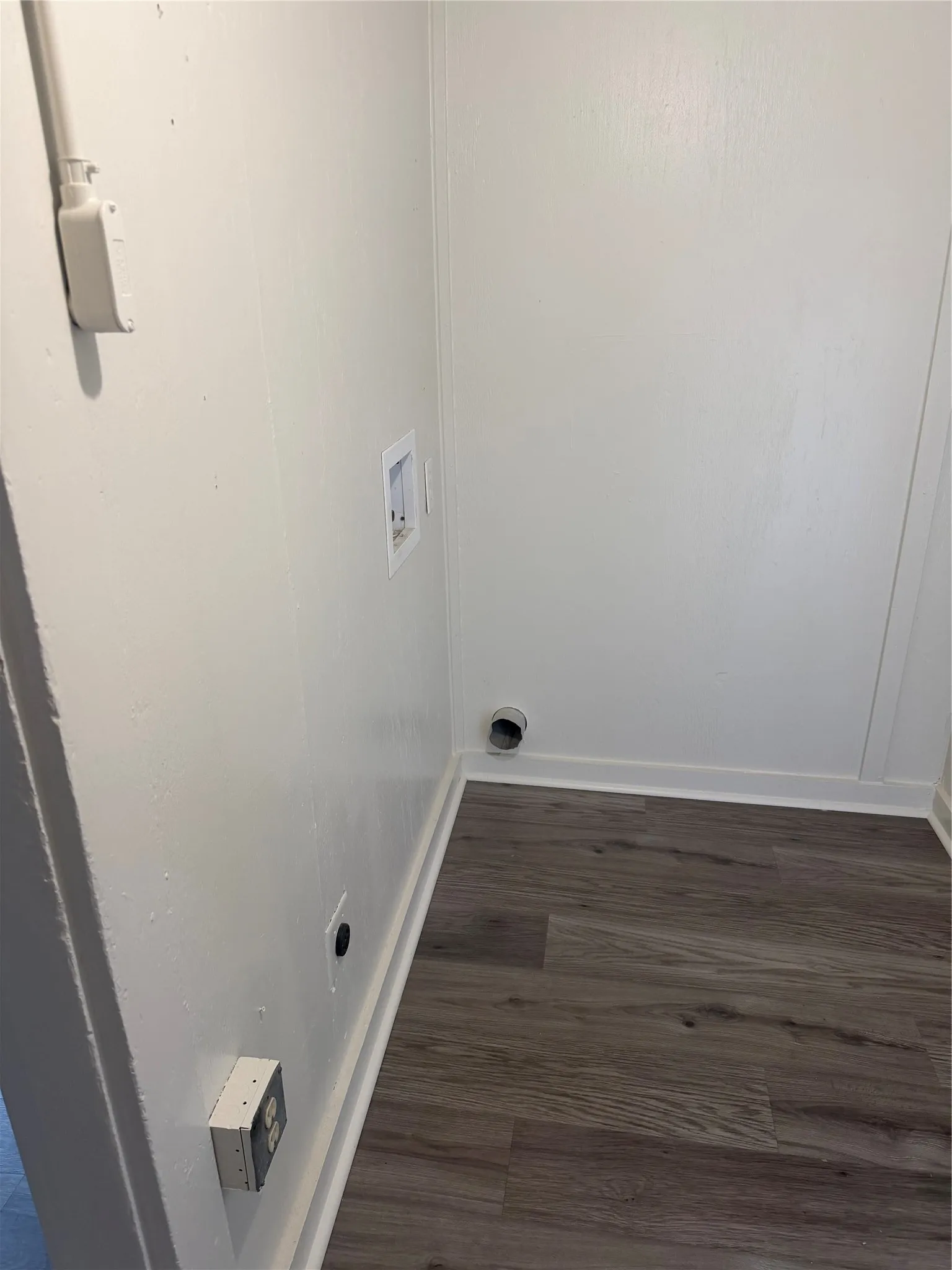 Dedicated utility space featuring wood-finish flooring, white walls, and essential hookups