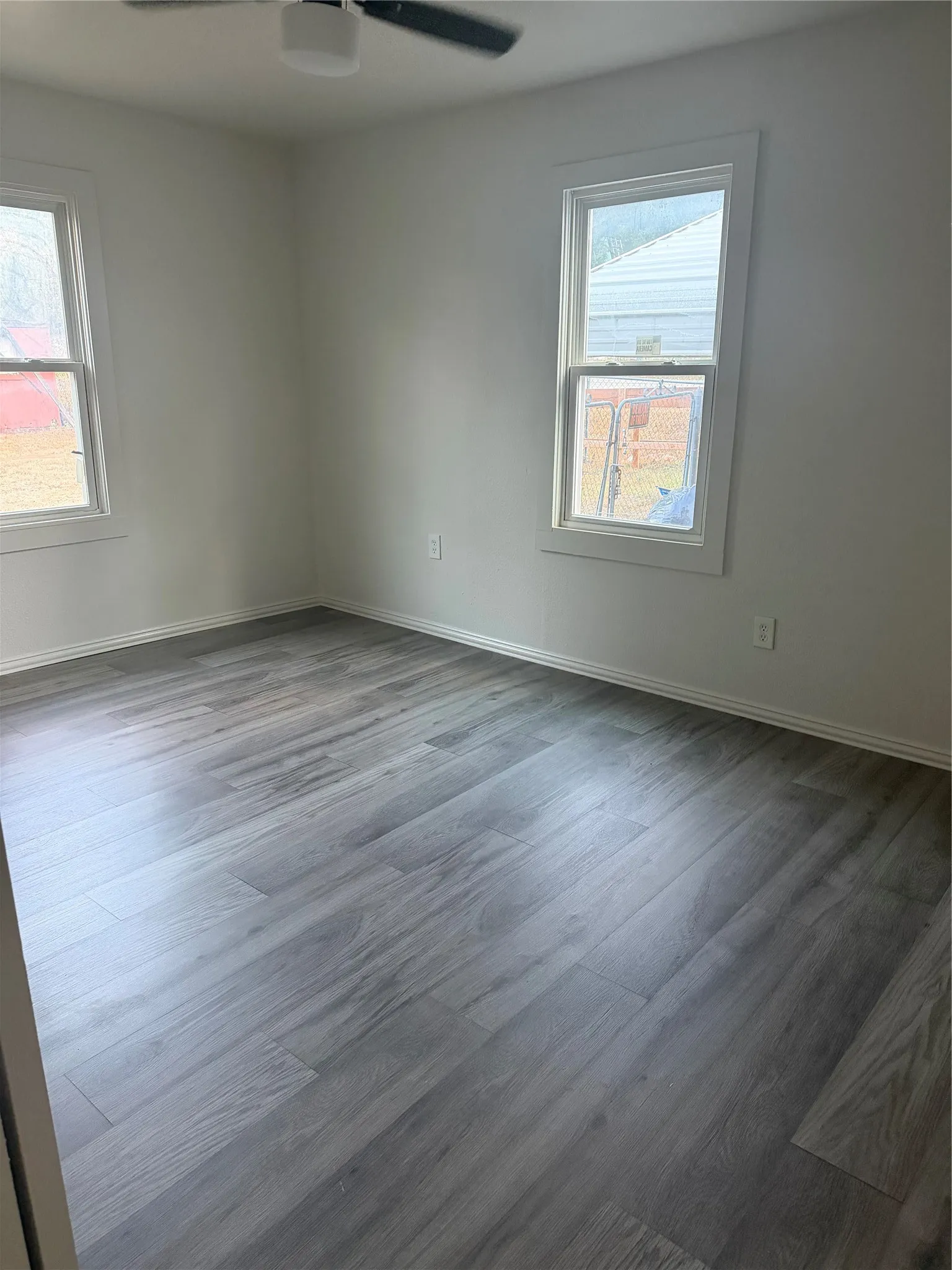 Wood-finish flooring, white walls, and two windows