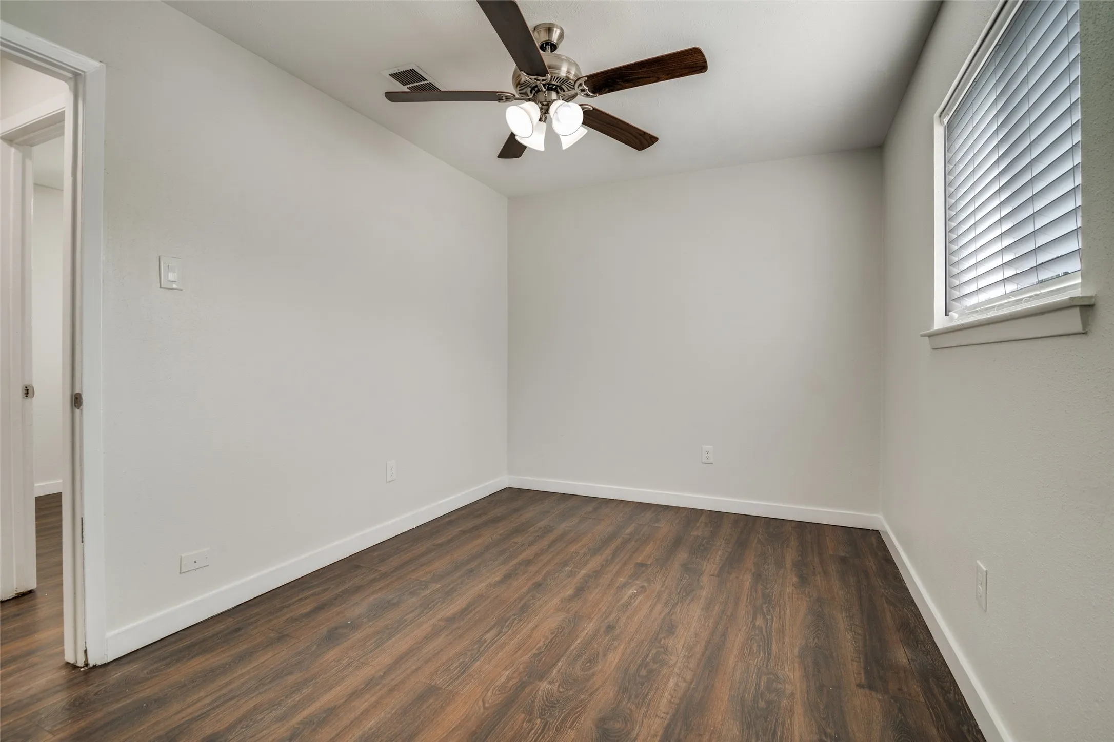 Unfurnished room featuring dark wood finished floors and ceiling fan