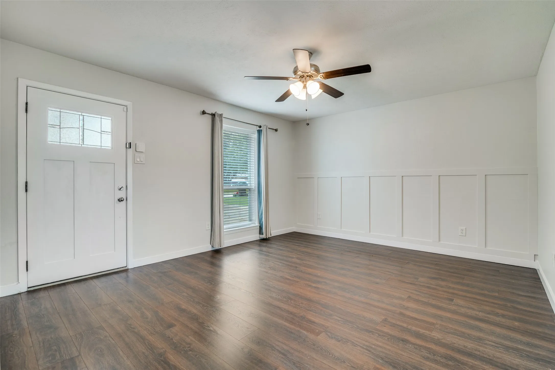 Entrance foyer with dark wood-type flooring, a ceiling fan, and a decorative wall