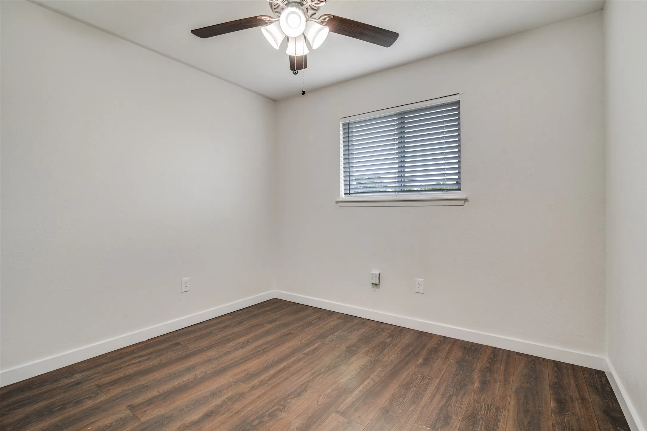 Empty room featuring dark wood-style flooring and a ceiling fan