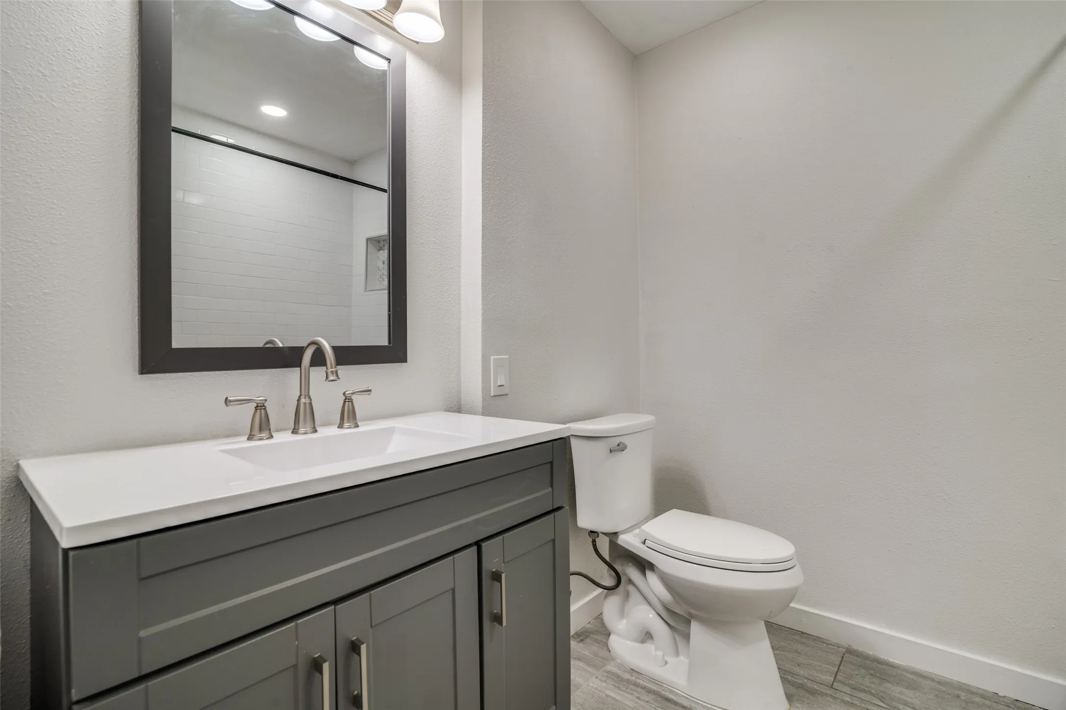 Bathroom with vanity, light wood finished floors, and a textured wall