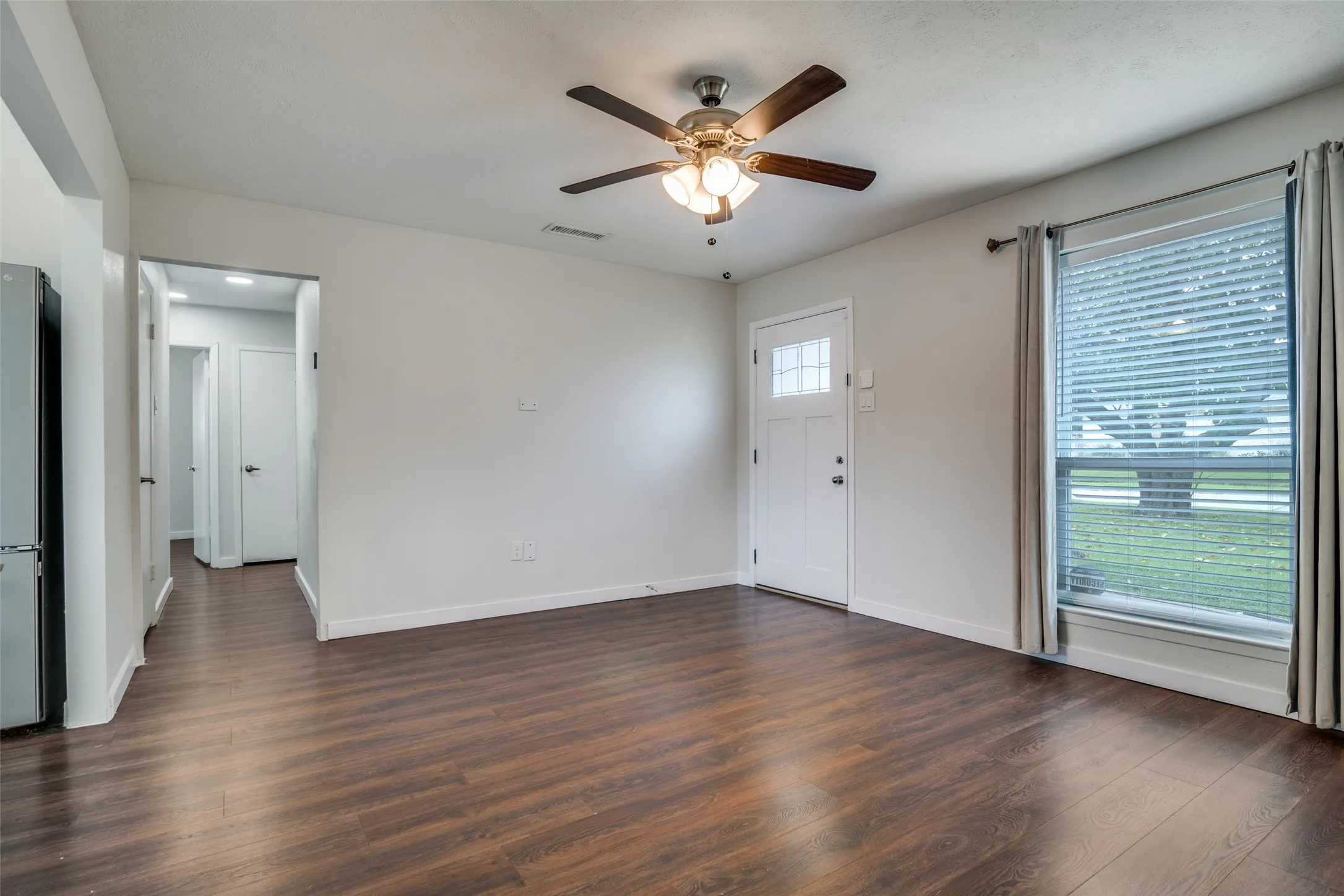 Unfurnished living room with dark wood-style floors and a ceiling fan