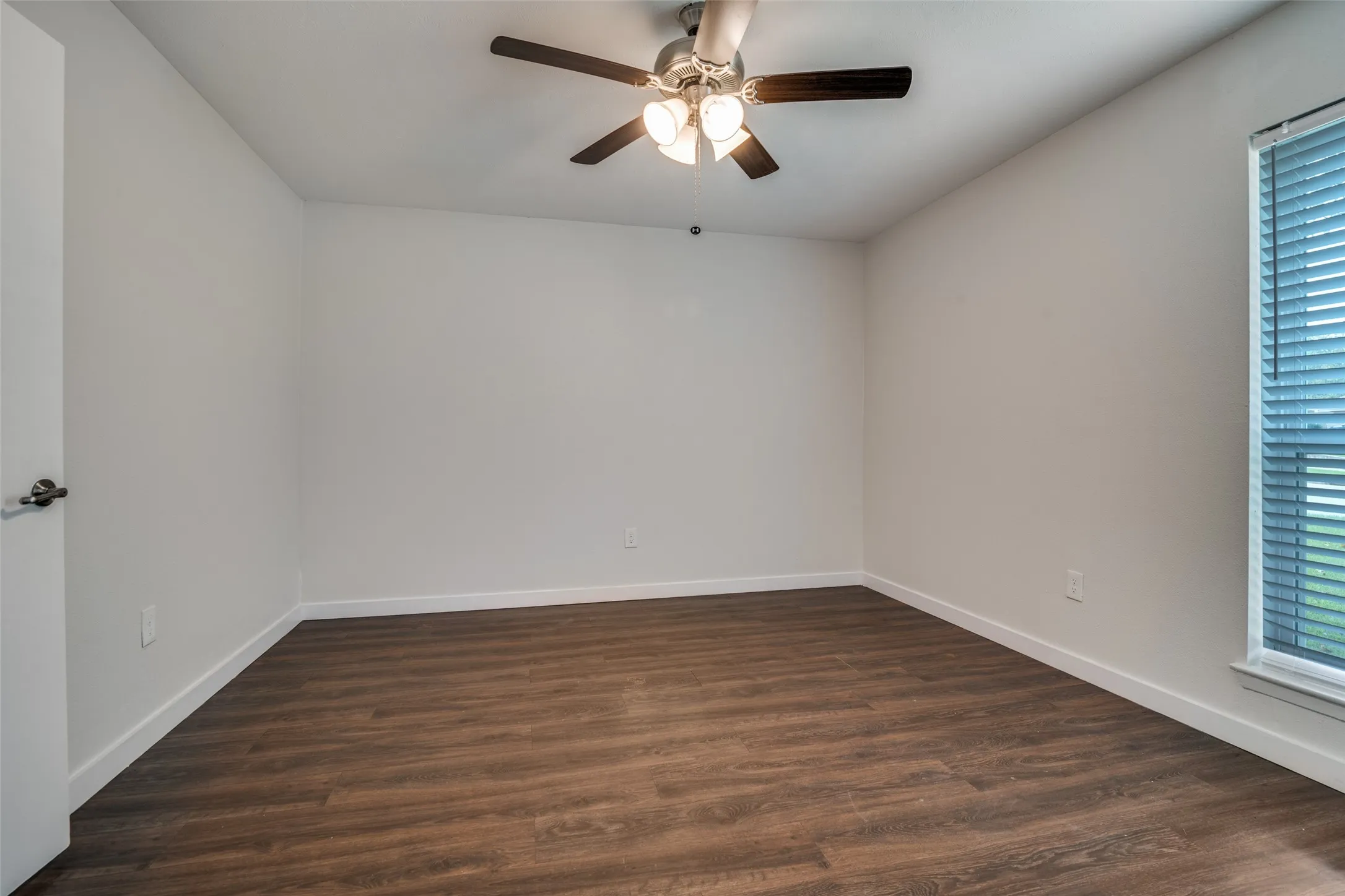 Empty room featuring dark wood finished floors, plenty of natural light, and ceiling fan