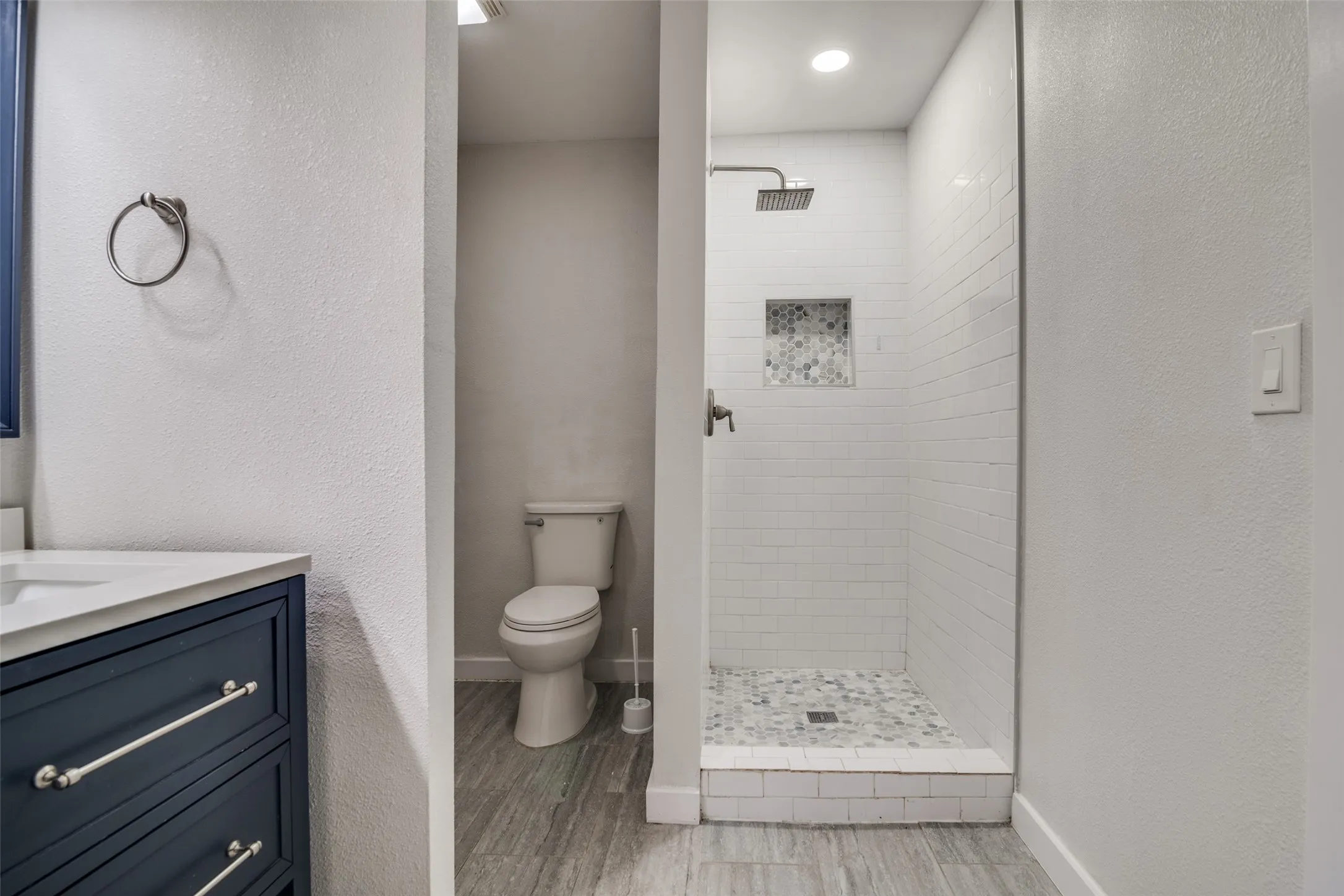 Bathroom with vanity, a textured wall, a stall shower, and light wood-type flooring