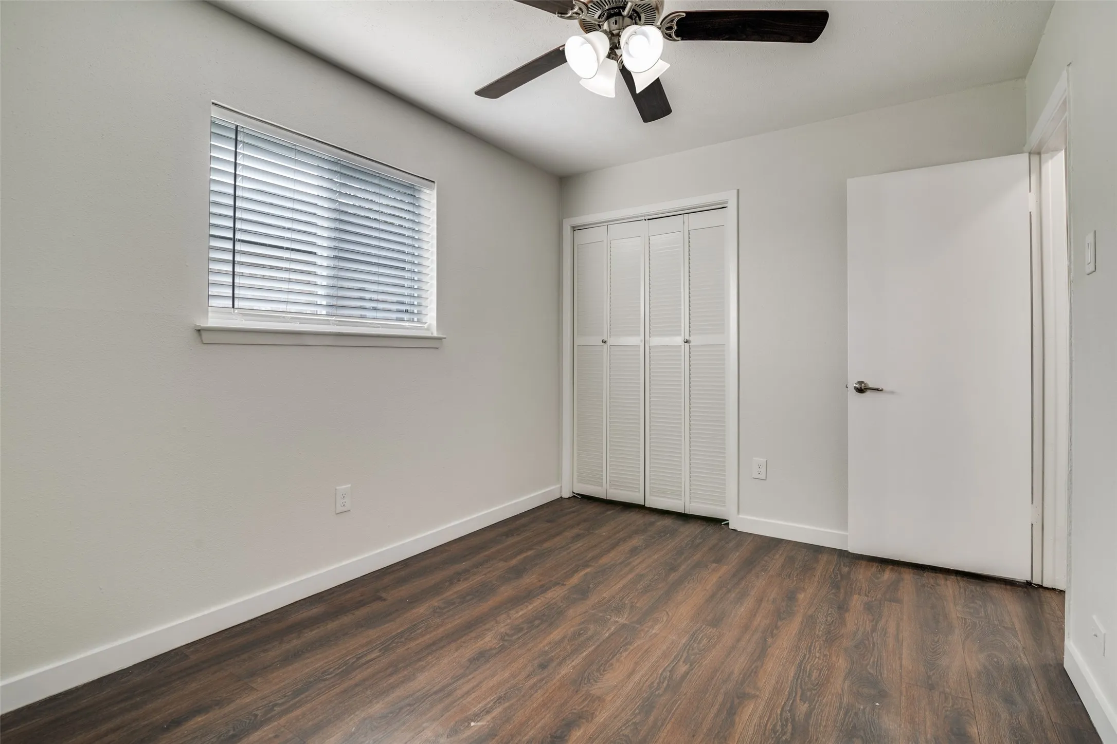 Unfurnished bedroom featuring dark wood-style floors, a ceiling fan, and a closet