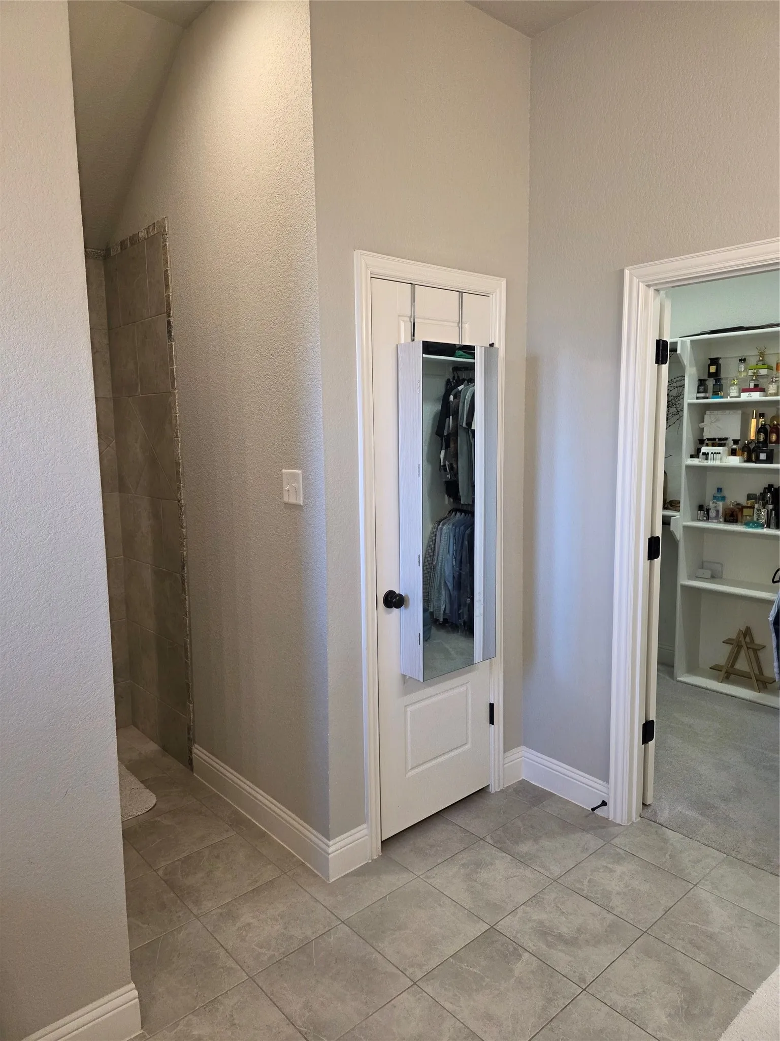 Full bath featuring a spacious closet, a stall shower, vaulted ceiling, and light tile patterned flooring